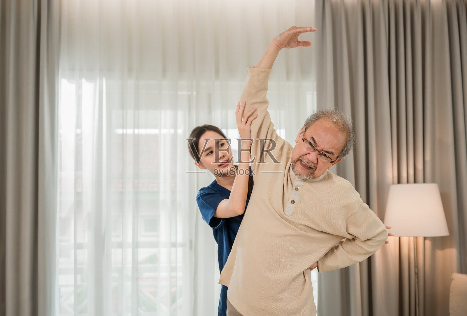 选择聚焦老人。专业的亚洲年轻女性物理治疗师，帮助老年男性伸展手臂和背部，在家里进行物理治疗和骨科康复。照片摄影图片