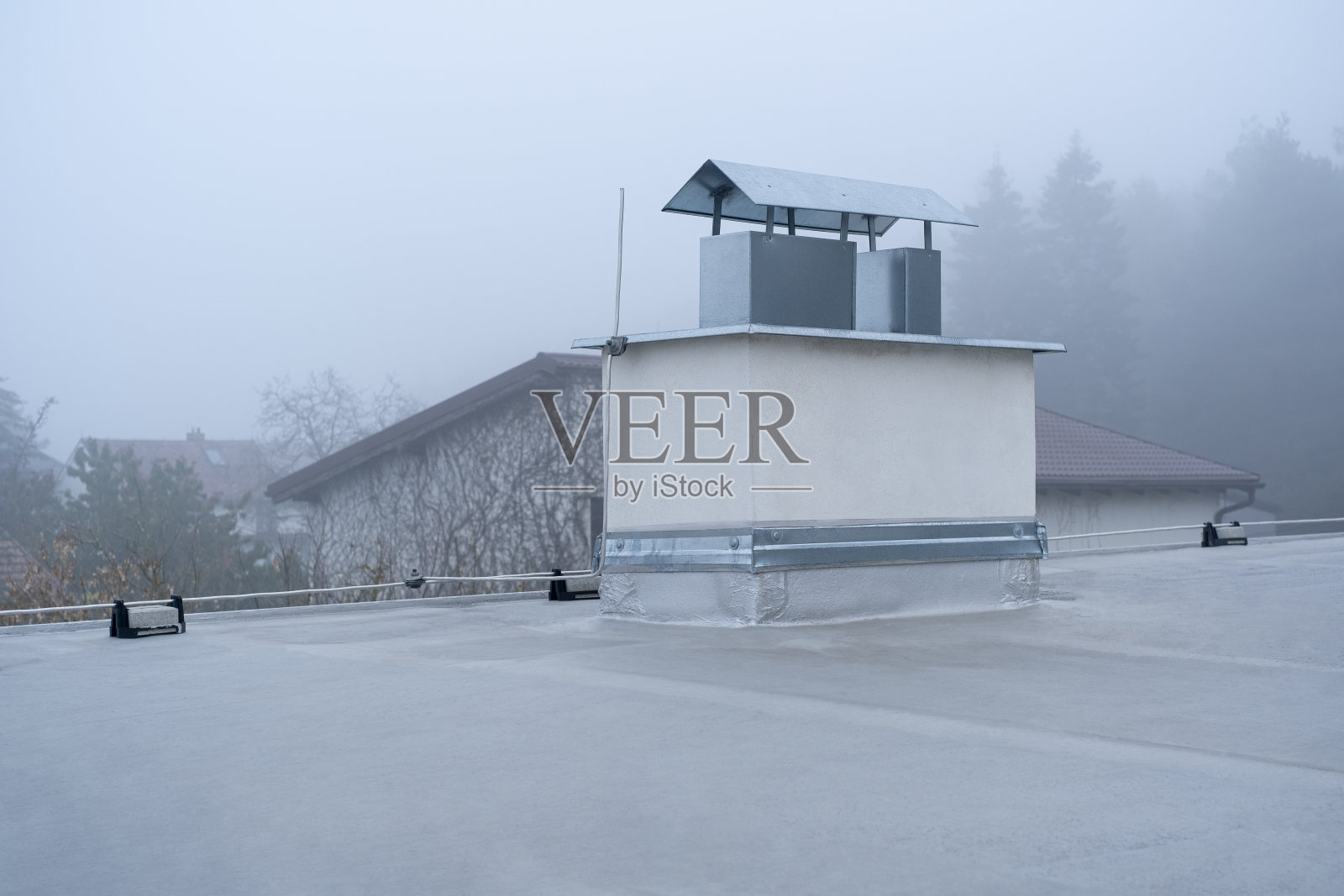 平顶覆盖沥青膜和银漆在私人住宅烟囱。多云雾霾雾天照片摄影图片