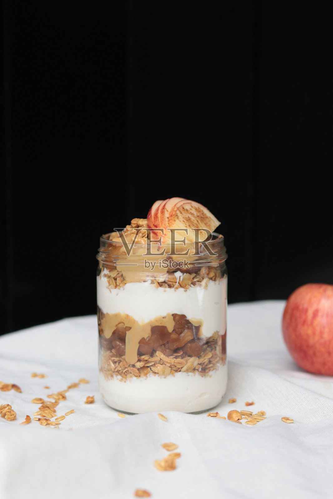 美味的苹果冻糕装在一个罐子里，放在白色的台布上，被孤立在黑色的背景上照片摄影图片