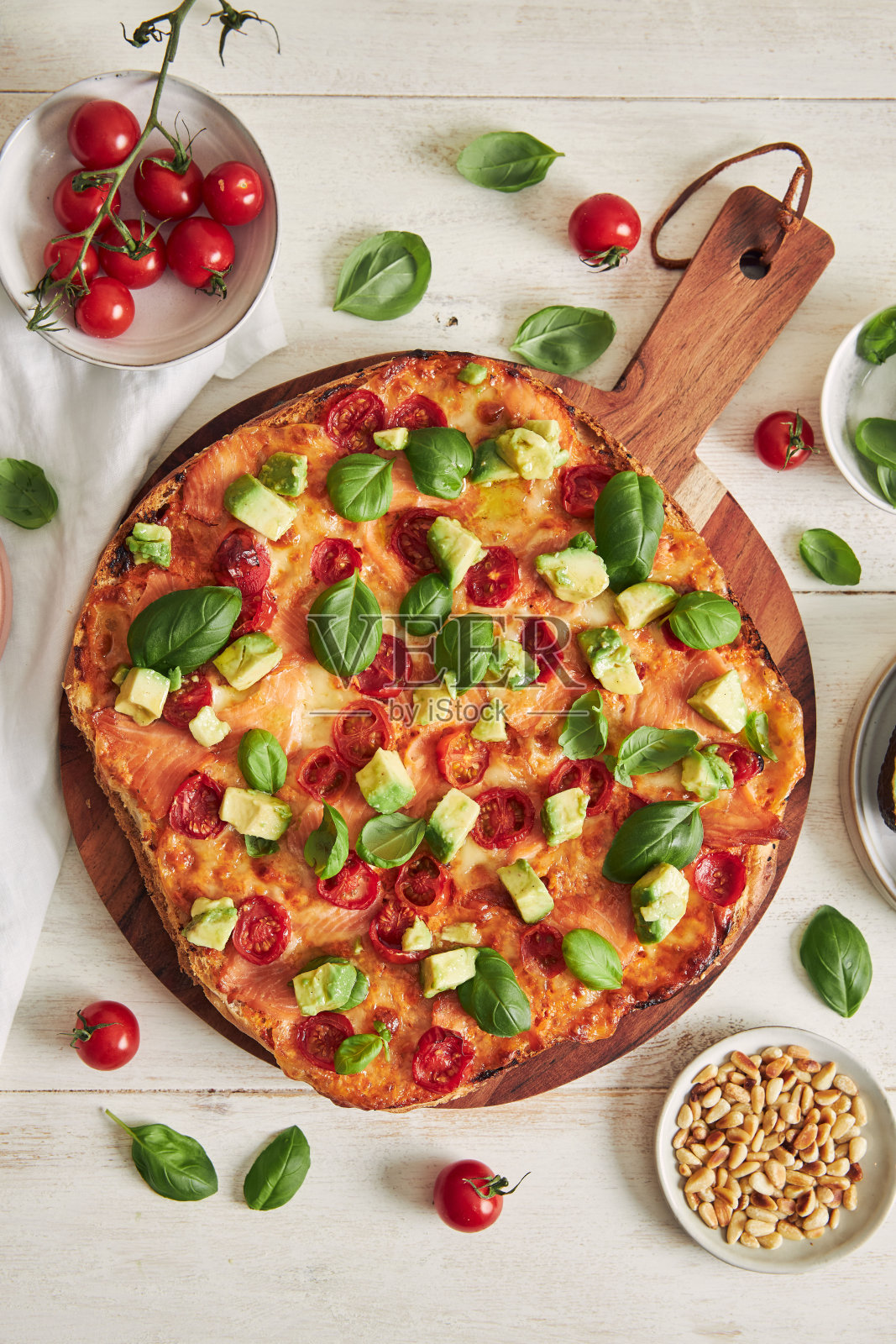 美味的整块披萨，配上三文鱼、融化的奶酪、菠菜和牛油果，放在桌子上的一块木板上照片摄影图片