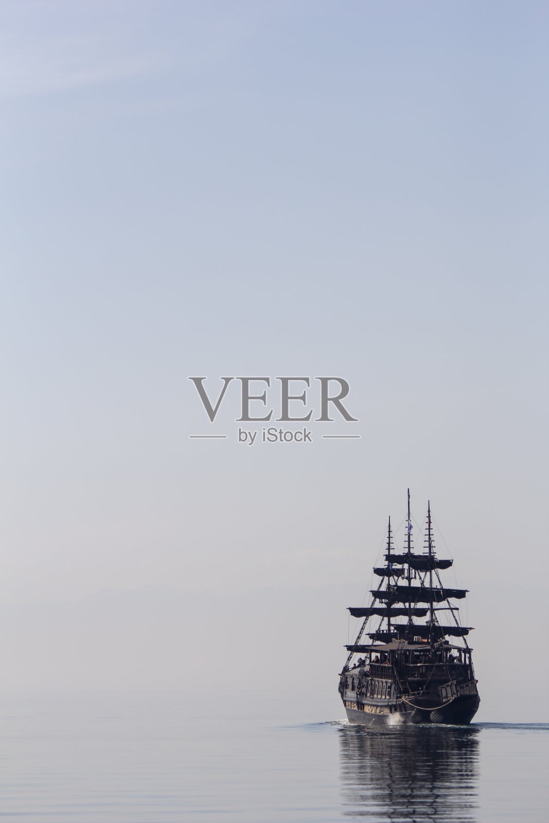 一艘高大的船在平静的水面上航行的垂直镜头照片摄影图片