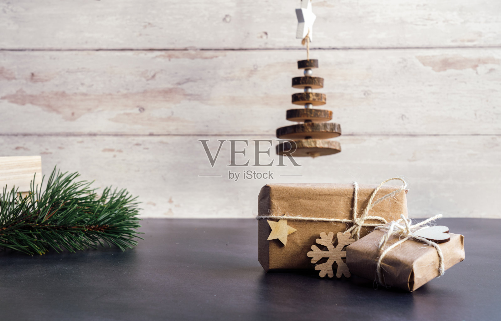 圣诞零浪费，环保包装。用牛皮纸包装的礼物与木制雪花和星星在一个深色背景的木桌上。生态圣诞假期理念，生态装饰用木材照片摄影图片