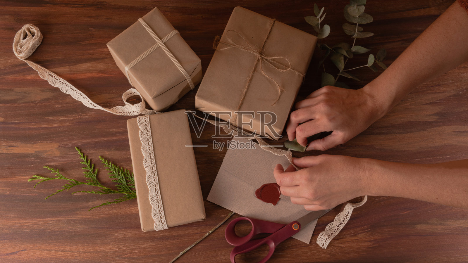 妇女双手准备礼盒与牛皮纸和黄麻丝带在木制背景照片摄影图片