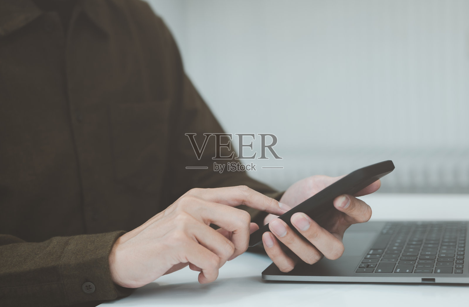 商务人士使用手机和笔记本电脑工作。男子用智能手机打字，照片摄影图片