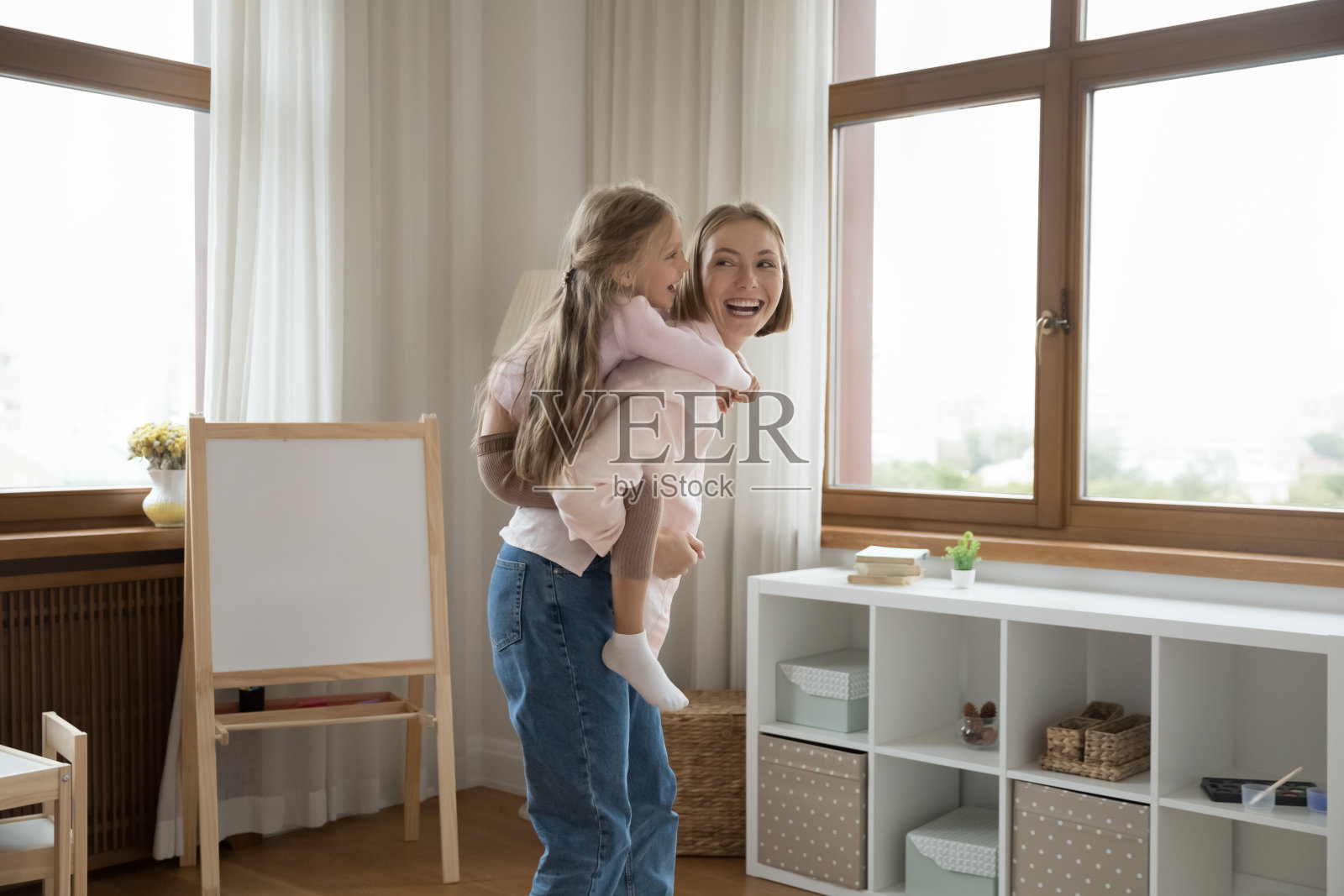 小女儿背着妈妈在室内进行有趣活泼的游戏照片摄影图片