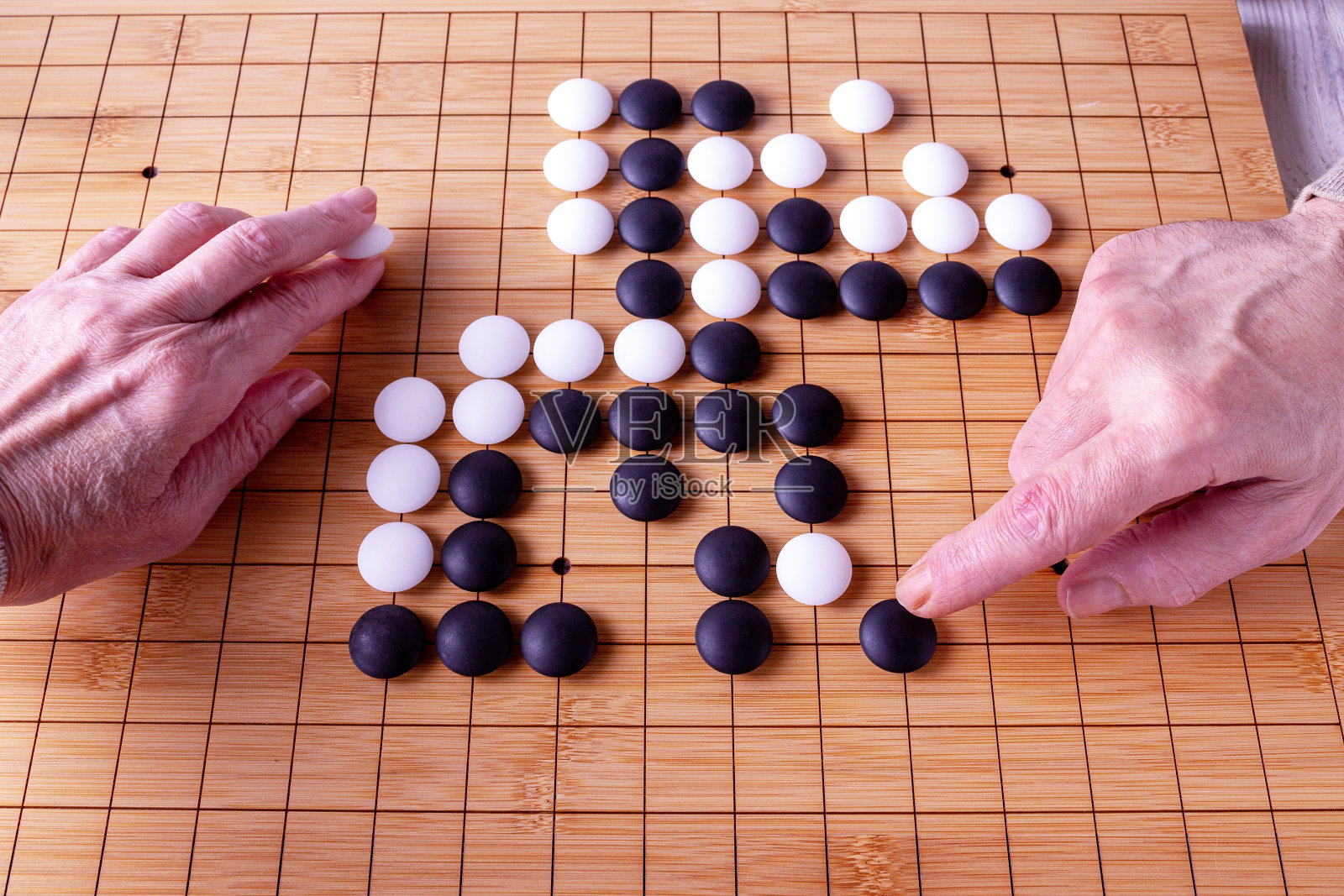 女人和男人的手移动goban上的石头，围棋游戏照片摄影图片