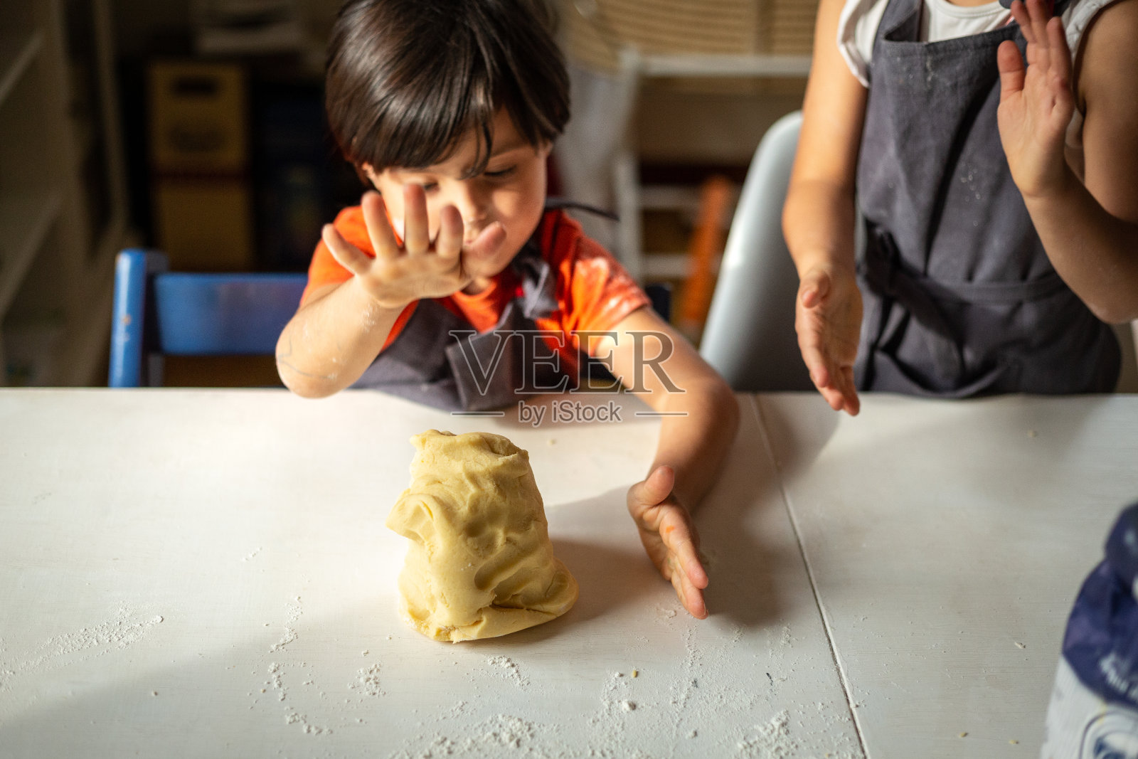 两个穿灰色围裙的女孩准备的面团照片摄影图片