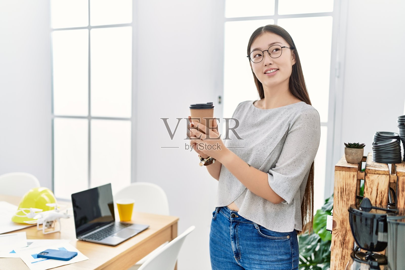 年轻的亚洲女人在办公室喝外卖咖啡照片摄影图片