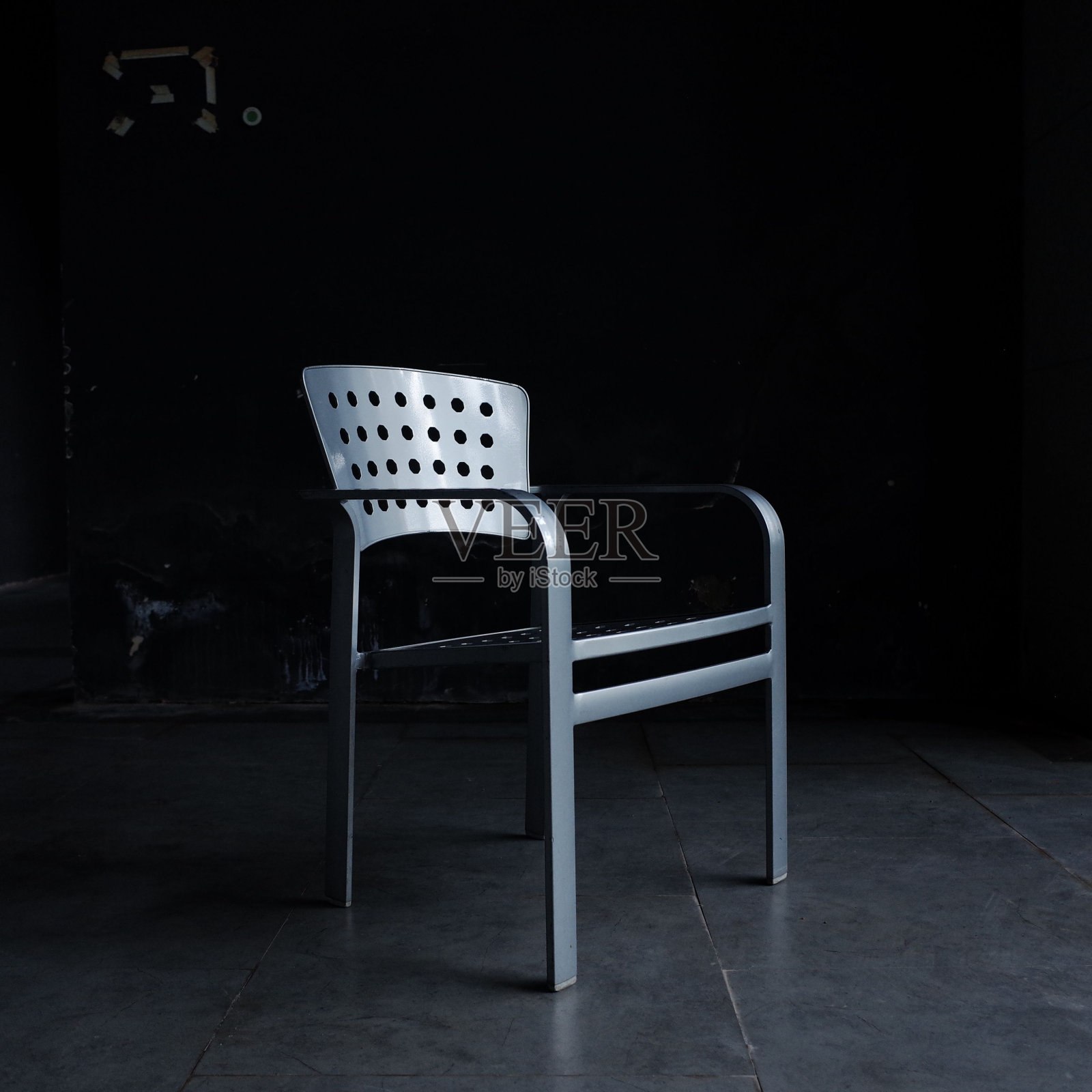 暗室里有破洞的塑料椅子。照片摄影图片