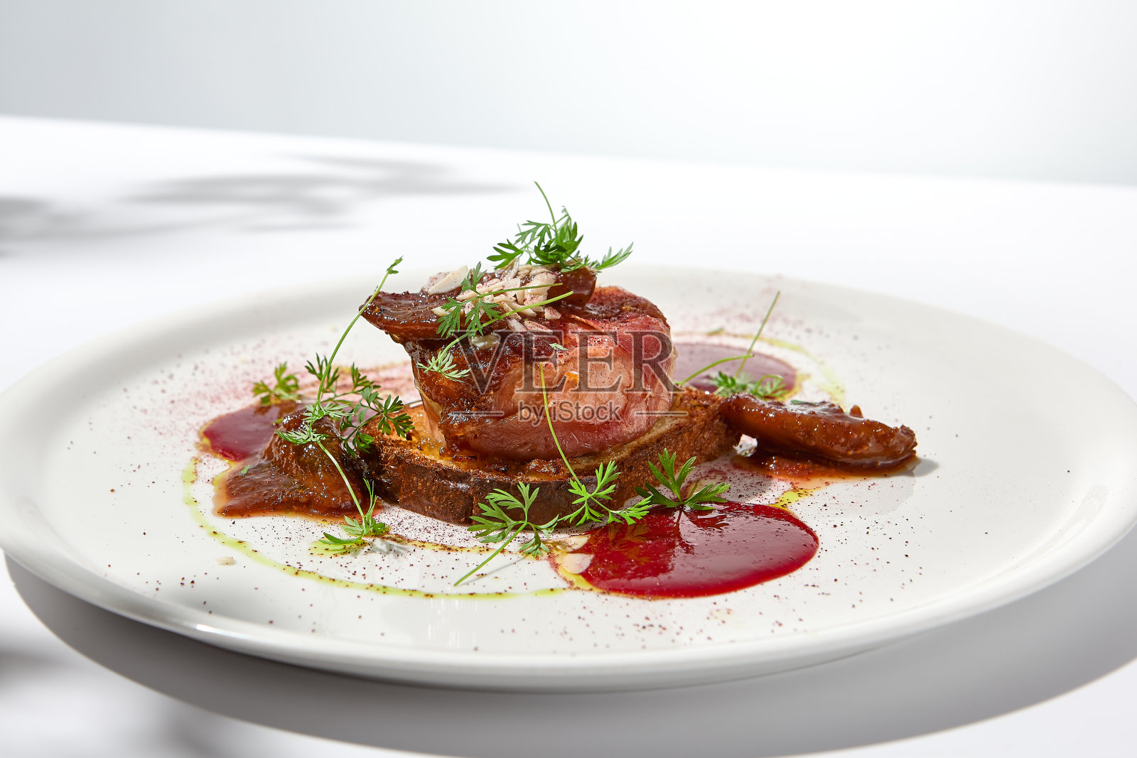 帕尔玛火腿烤卡门培尔干酪配奶油蛋卷配浆果酱。优雅的食物——夏季菜单中的卡门贝尔干酪和火腿开胃菜。高级餐厅里的奶酪开胃菜。夏季菜单。照片摄影图片