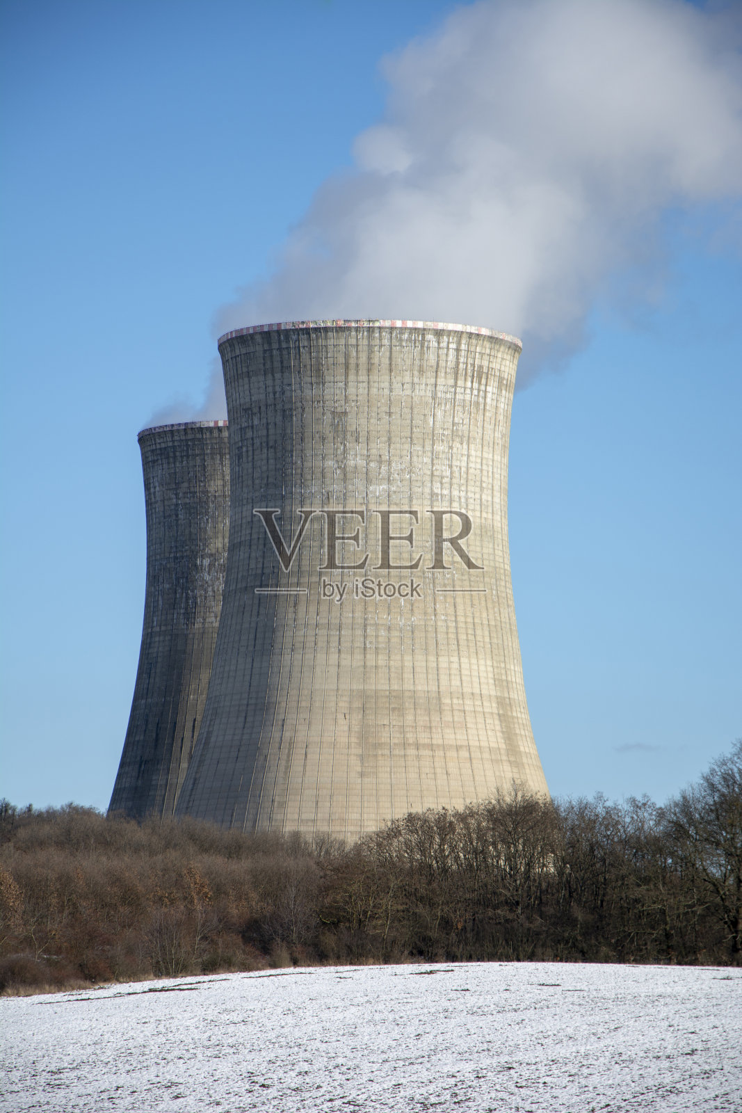 核电站在冬天。冷却水塔。蓝天为背景。农田上的雪。照片摄影图片