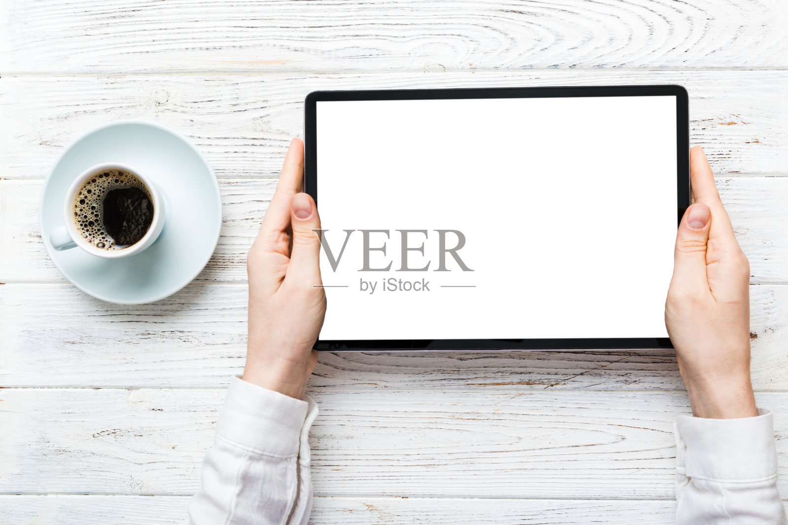 近距离的形象妇女手拿数字平板电脑空白复制空间屏幕为您的短信或促销内容从桌子上一杯咖啡。一个女人的手拿着空白的平板设备照片摄影图片