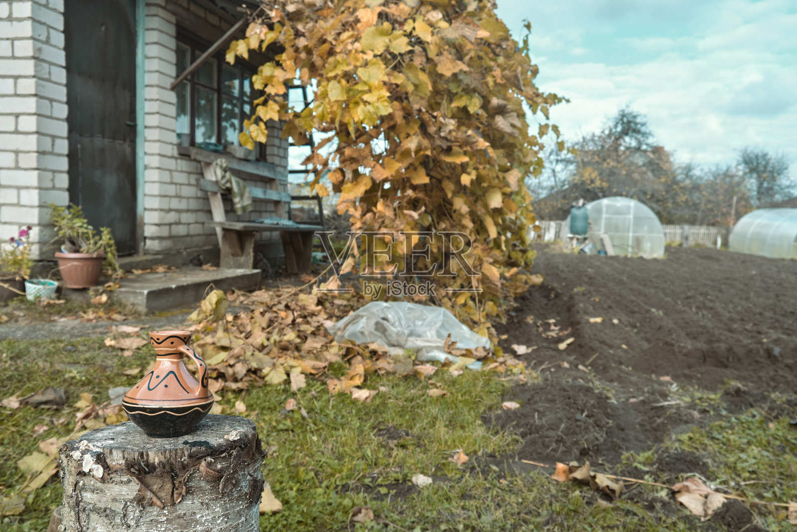 传统的陶罐罐在原木在房子的院子与乡村木栅栏的背景老陶瓷锅照片摄影图片