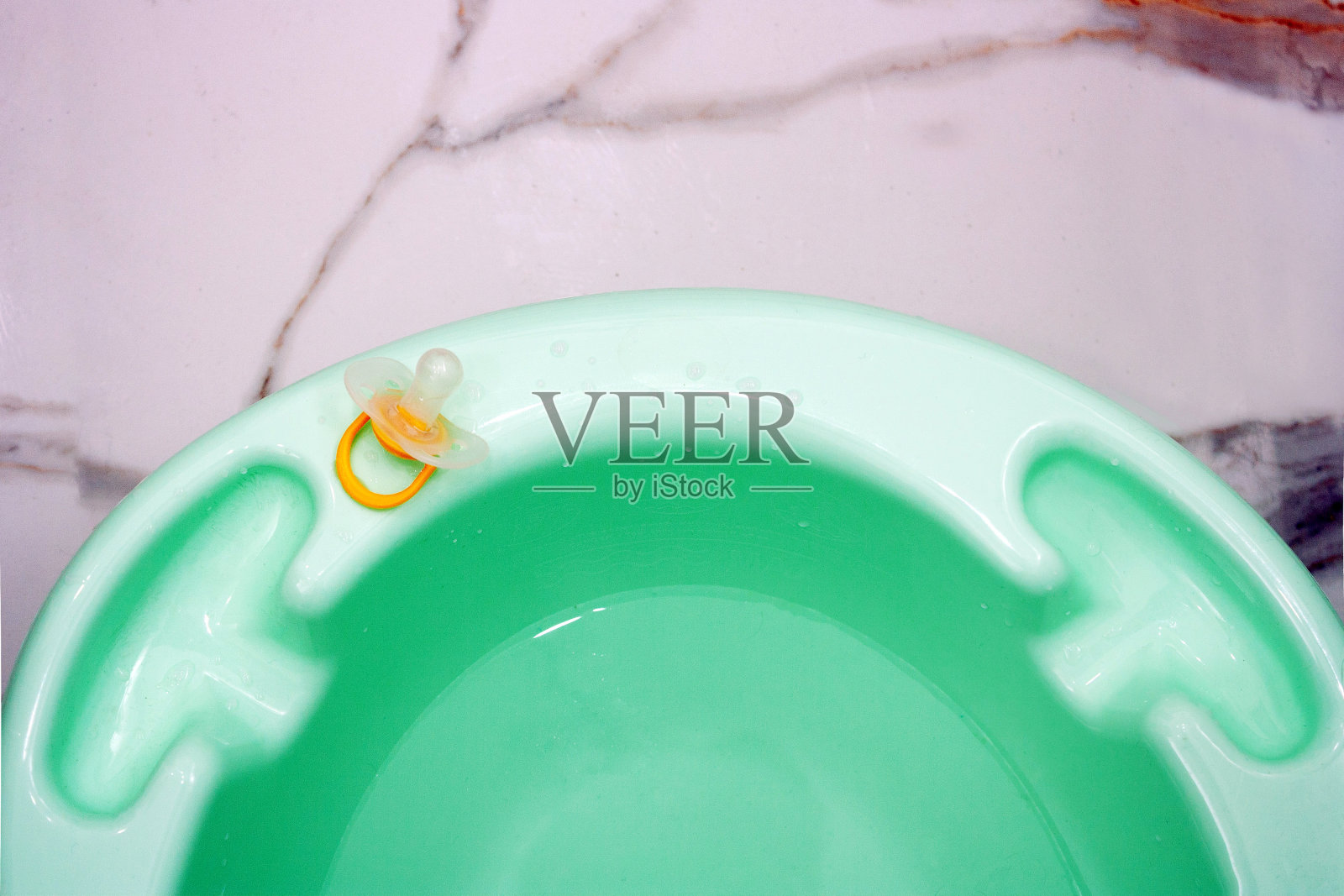 一个用来给婴儿洗澡的浴缸的碎片，放在灰色大理石弗洛上照片摄影图片