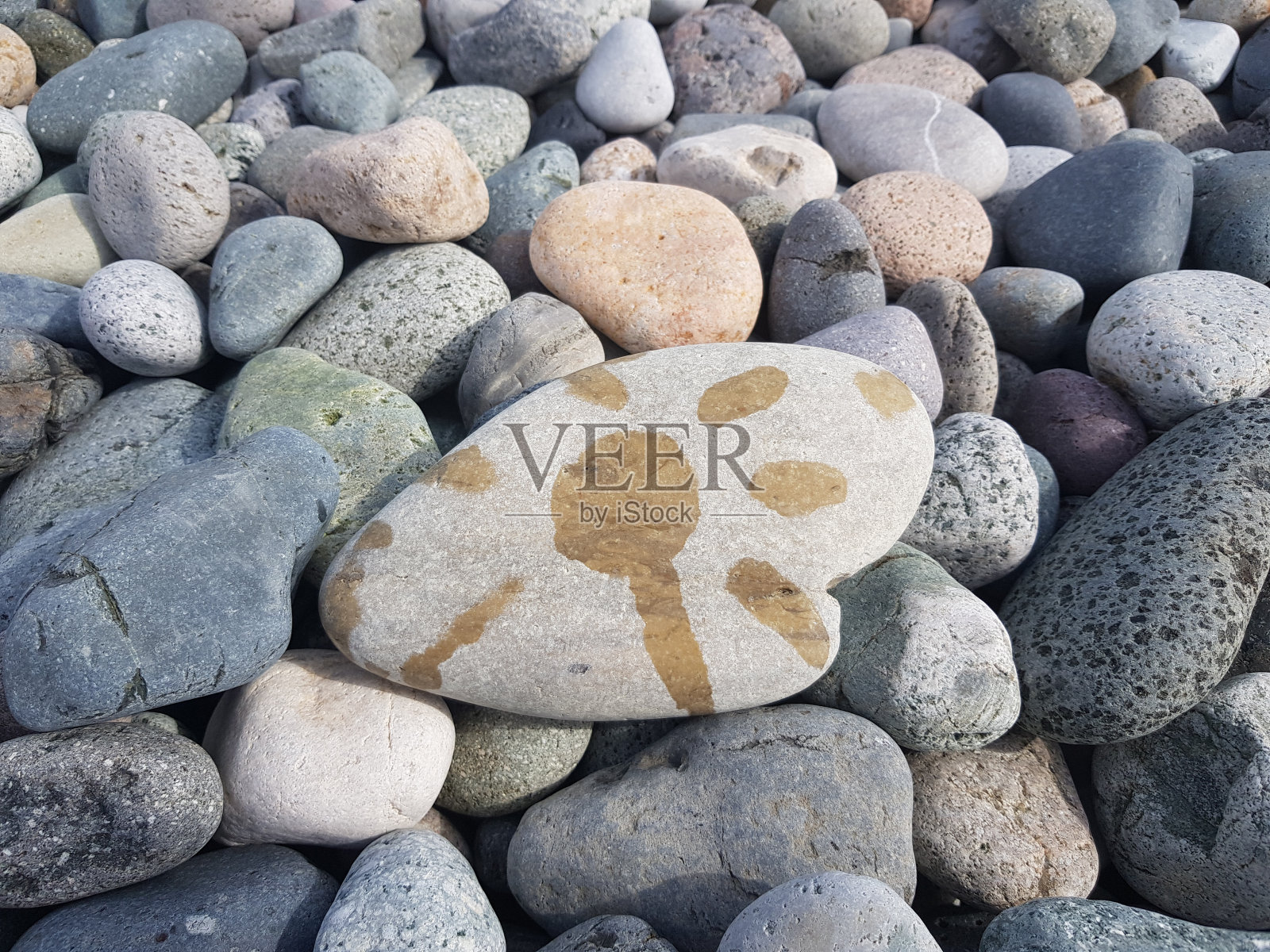 沙滩上灰色鹅卵石的特写，画着太阳照片摄影图片