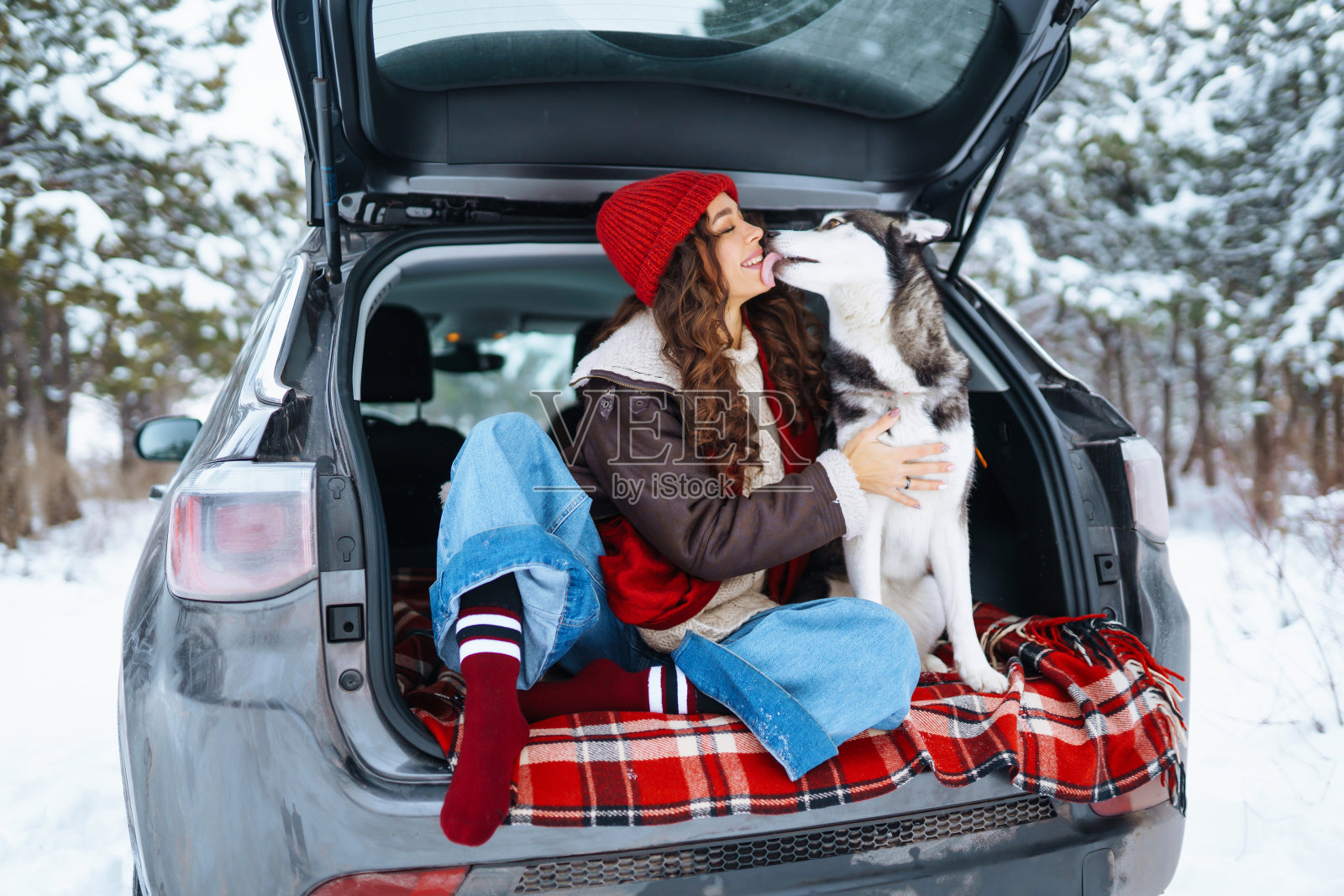 年轻女子和可爱的哈士奇狗享受户外进入汽车。照片摄影图片