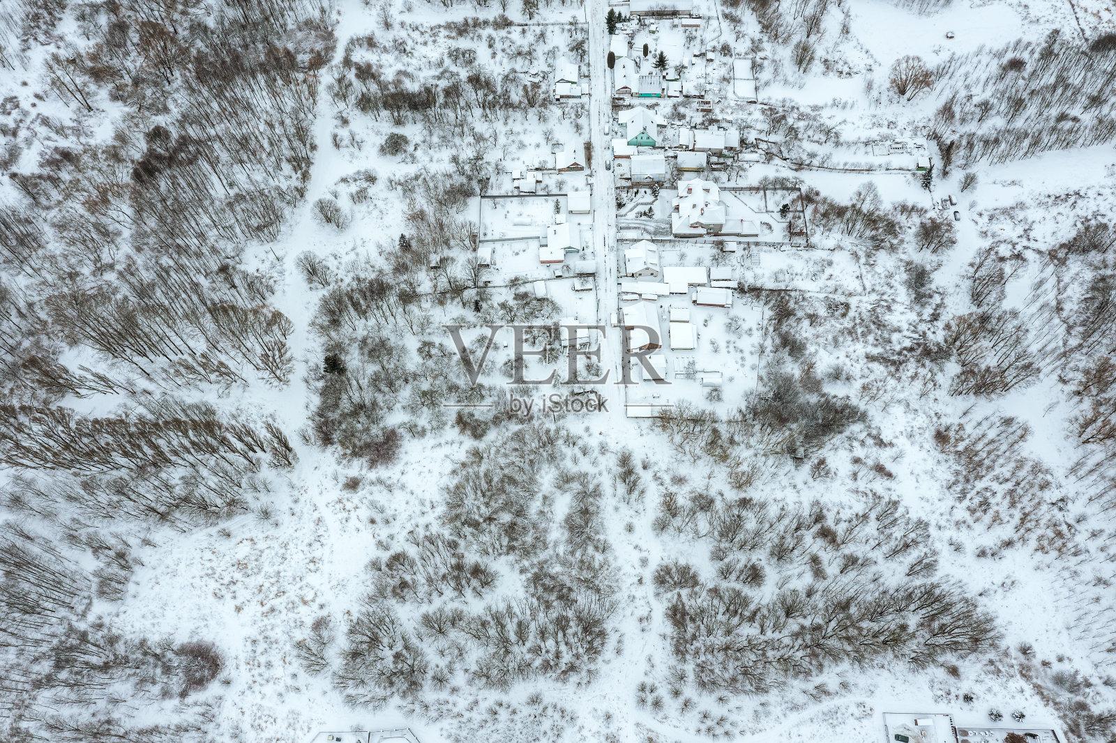 乡村景观，小雪覆盖的村庄在冬季森林。无人机拍摄的照片。照片摄影图片