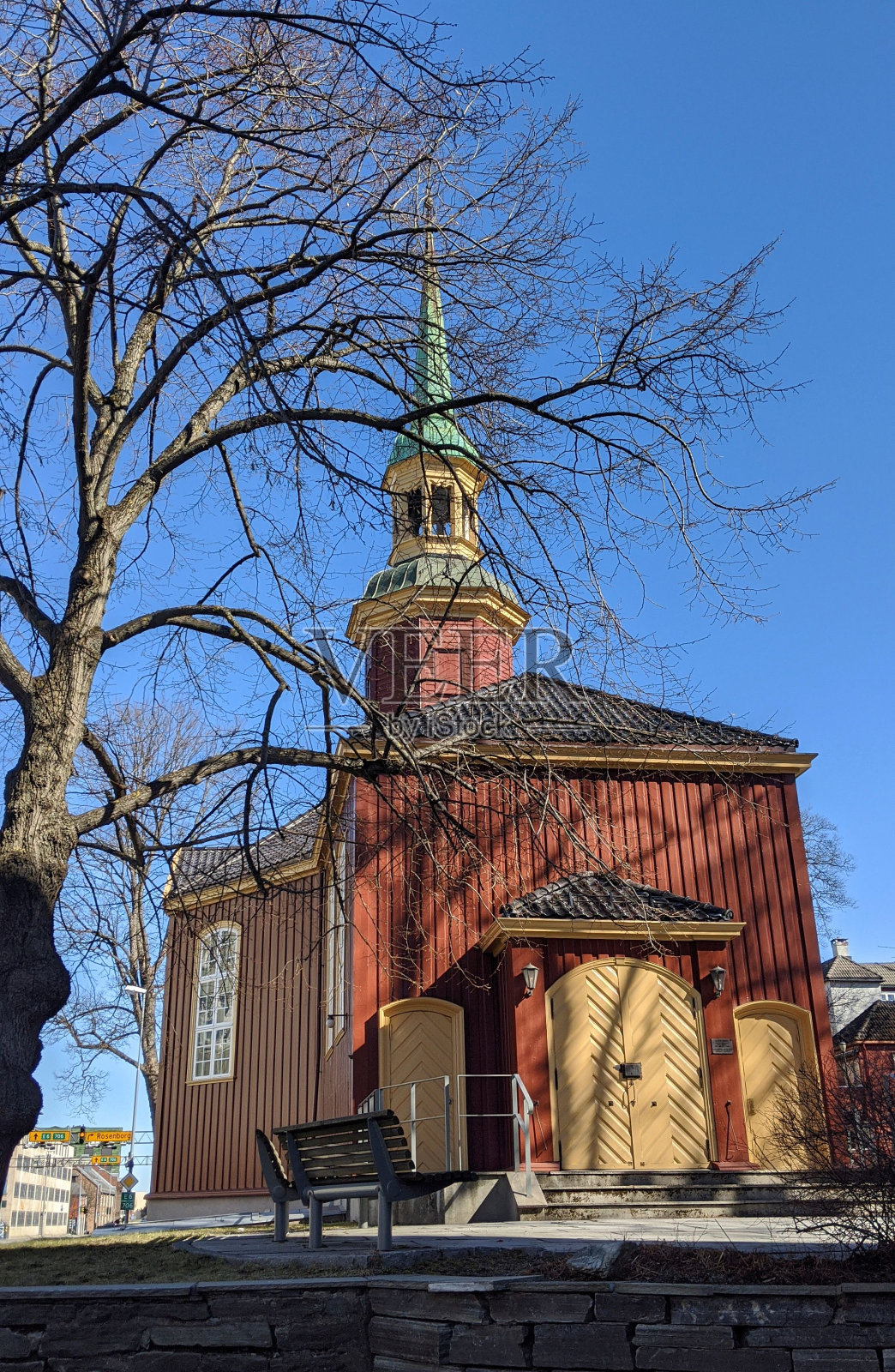 垂直的老木教堂，光秃秃的树和前面的长凳照片摄影图片