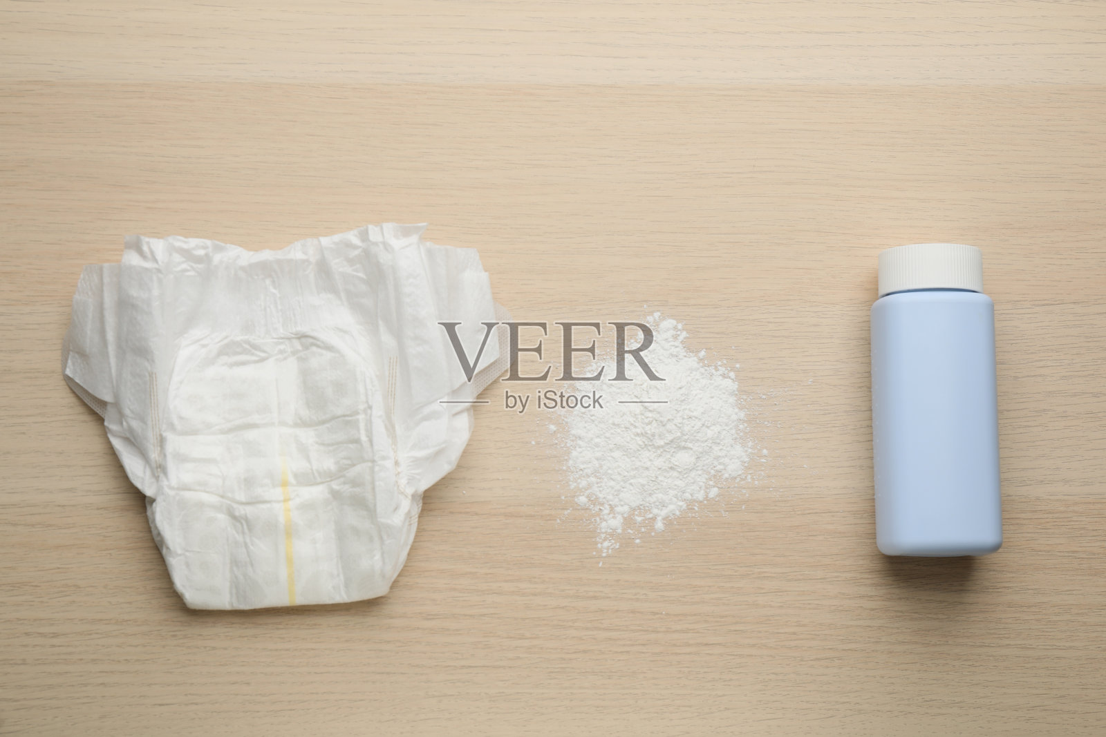 将粉和纸尿裤铺在木制背景上，平铺。婴儿护理用品照片摄影图片