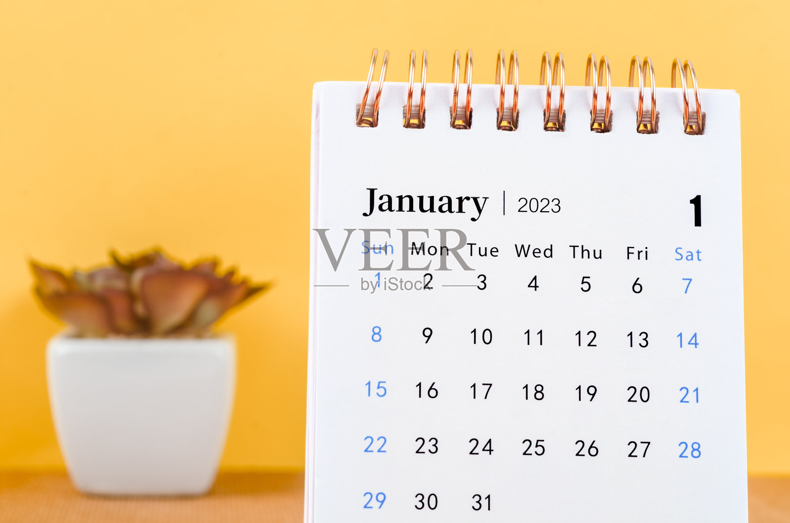 关闭黄色背景的2023年1月2023台历。照片摄影图片