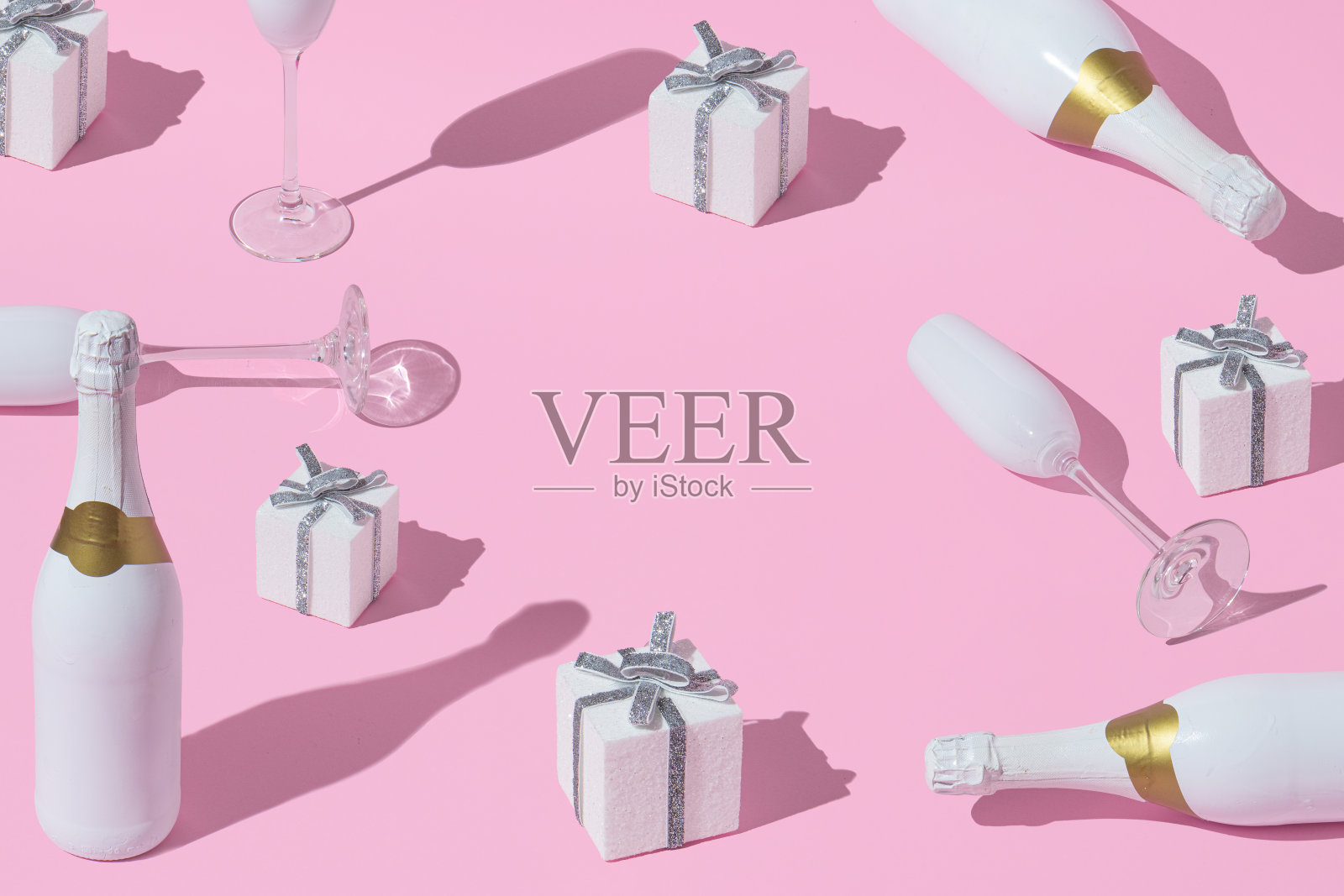 圣诞创意布局与香槟瓶，玻璃杯和礼物在柔和的粉红色背景。最简单的新年或圣诞节庆祝想法。副本的空间。照片摄影图片