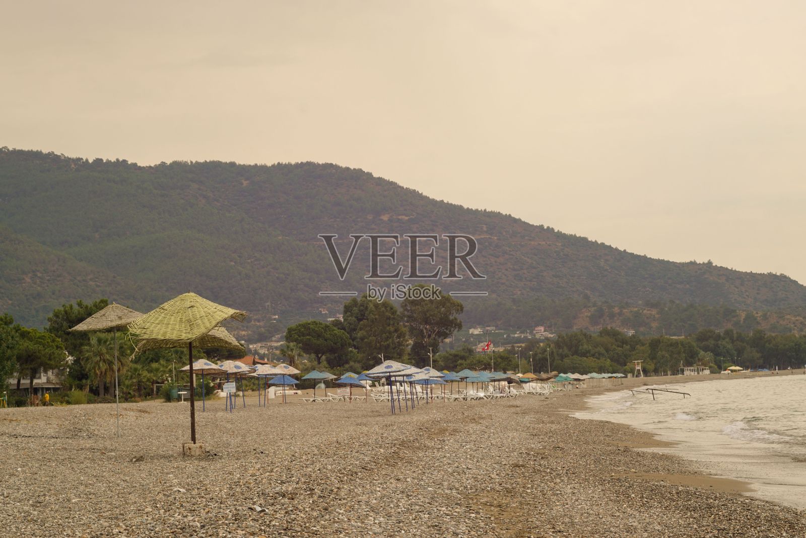 秋天的空海滩，开着遮阳伞，背景是山照片摄影图片