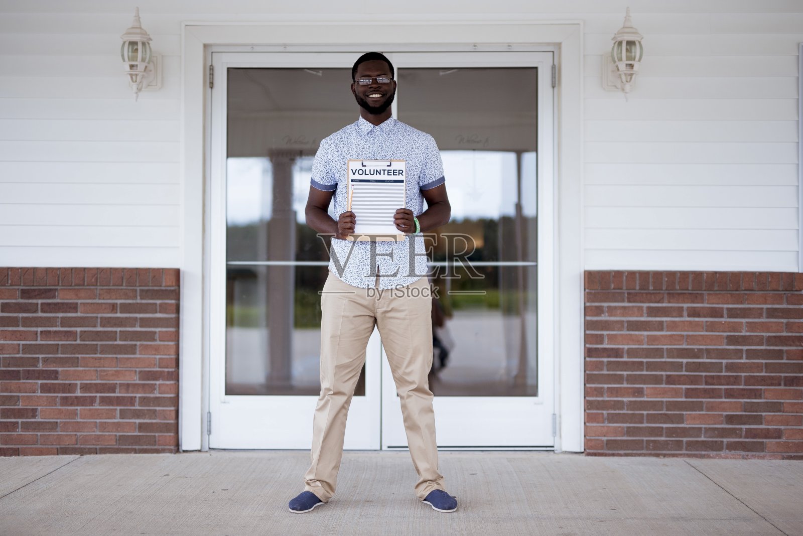 一名男子站在教堂附近，手里拿着一个志愿者剪贴板照片摄影图片