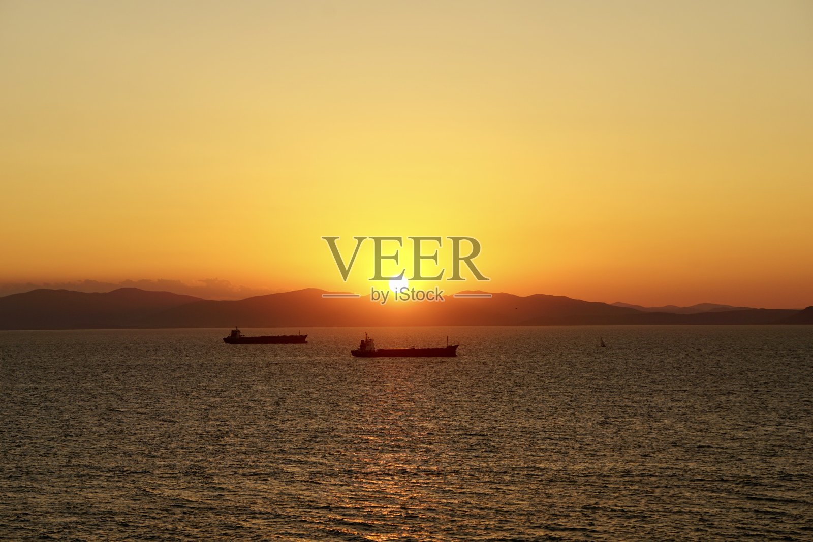 海上夕阳西下，工业船停在路边。船在日落时出海。红日照进了船停泊的山海。日本海的日落。照片摄影图片