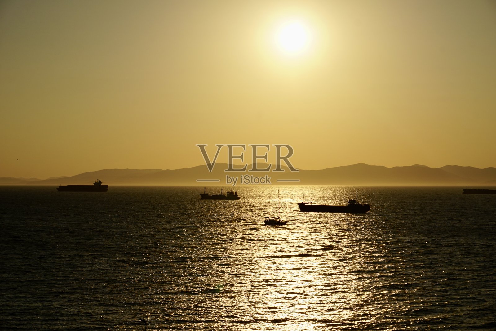 海上夕阳西下，工业船停在路边。船在日落时出海。红日照进了船停泊的山海。日本海的日落。照片摄影图片