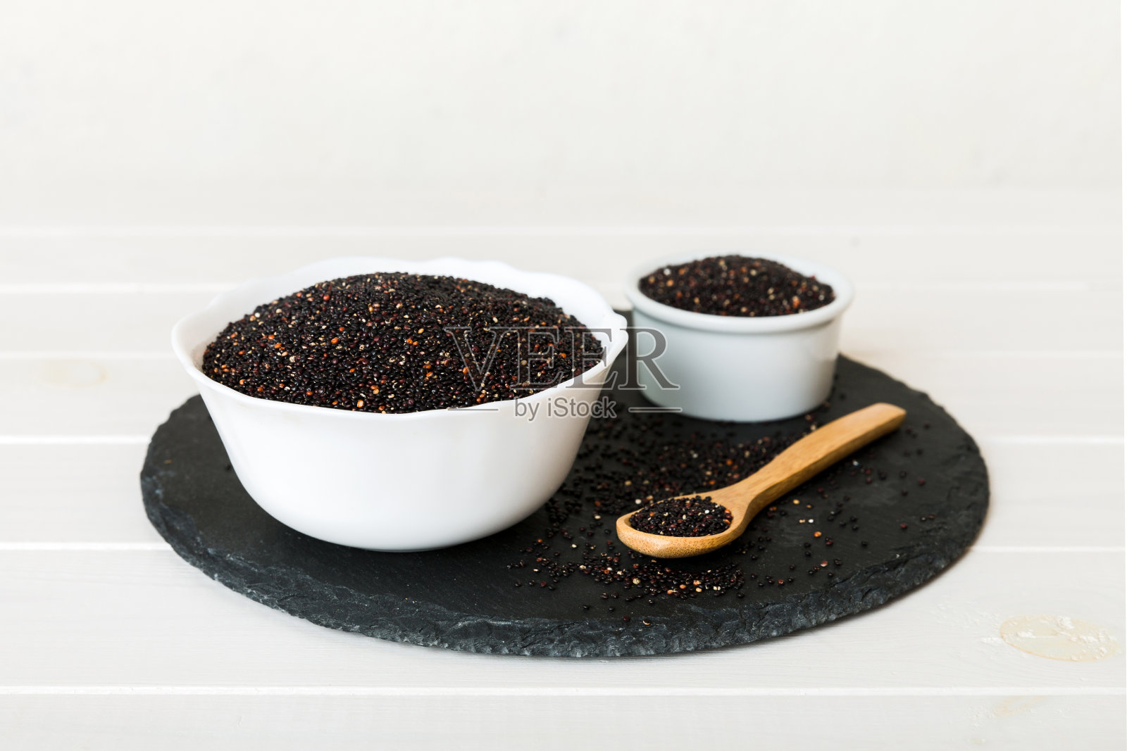 在碗和勺子里的藜麦种子在彩色背景上。健康的kinwa在小碗里。健康的超级食物照片摄影图片