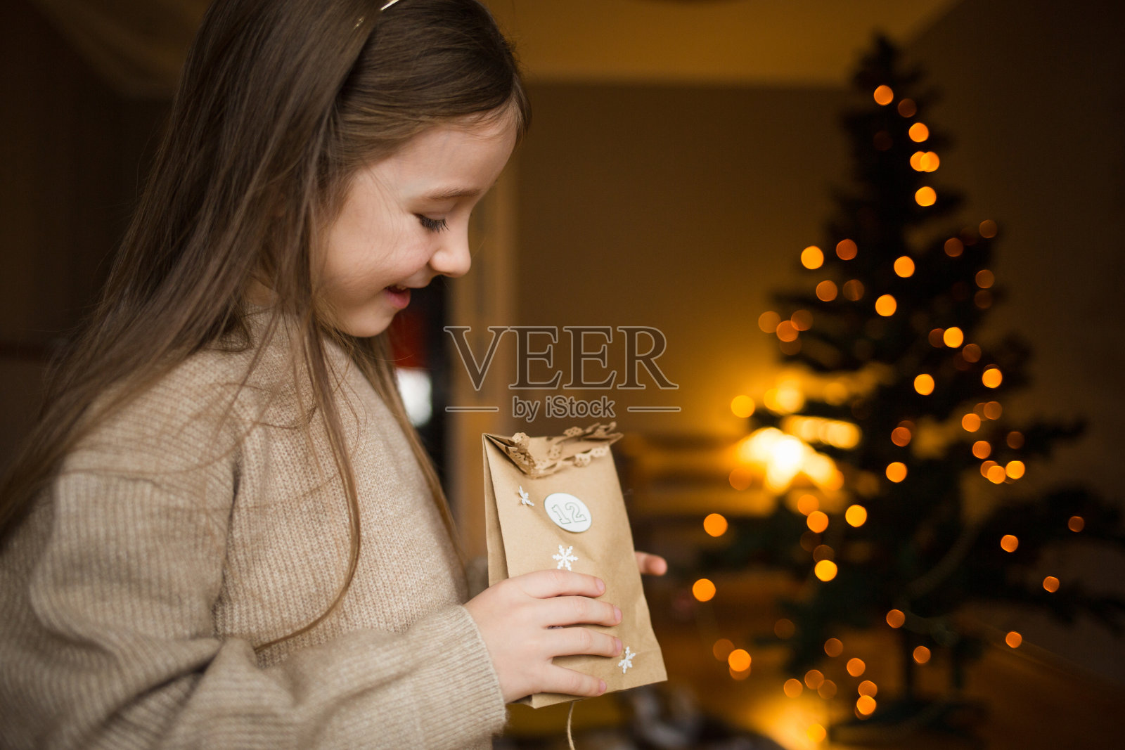 孩子打开信封的降临日历背景的圣诞树灯照片摄影图片