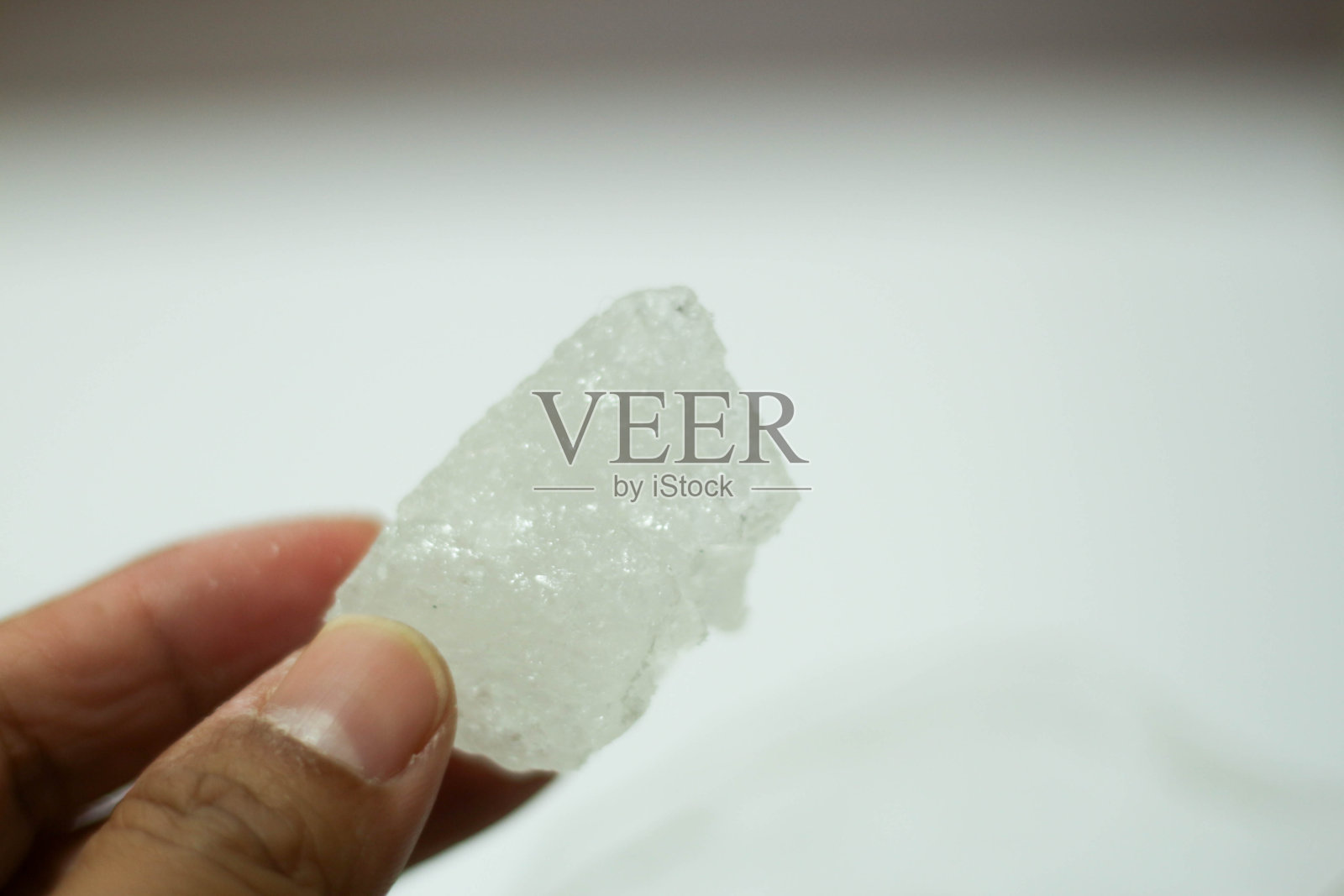 手拿冰糖，白色背景照片摄影图片