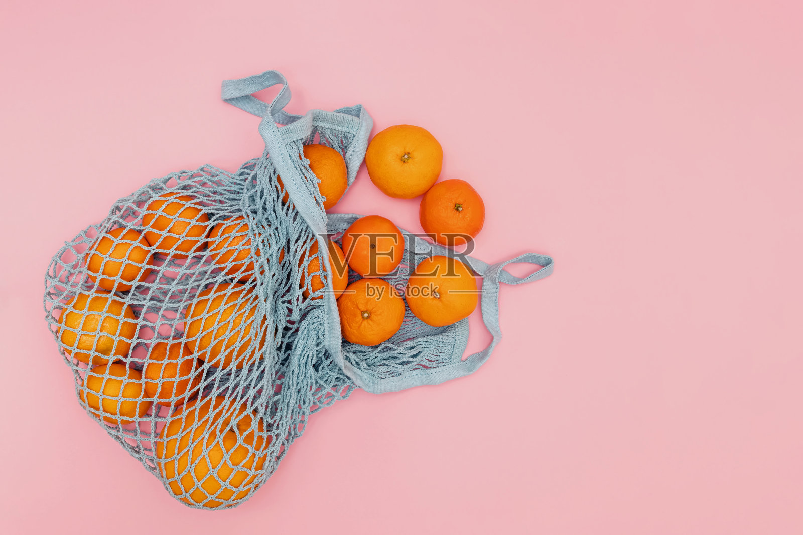 橙色柑橘类水果在刺袋粉红色背景照片摄影图片