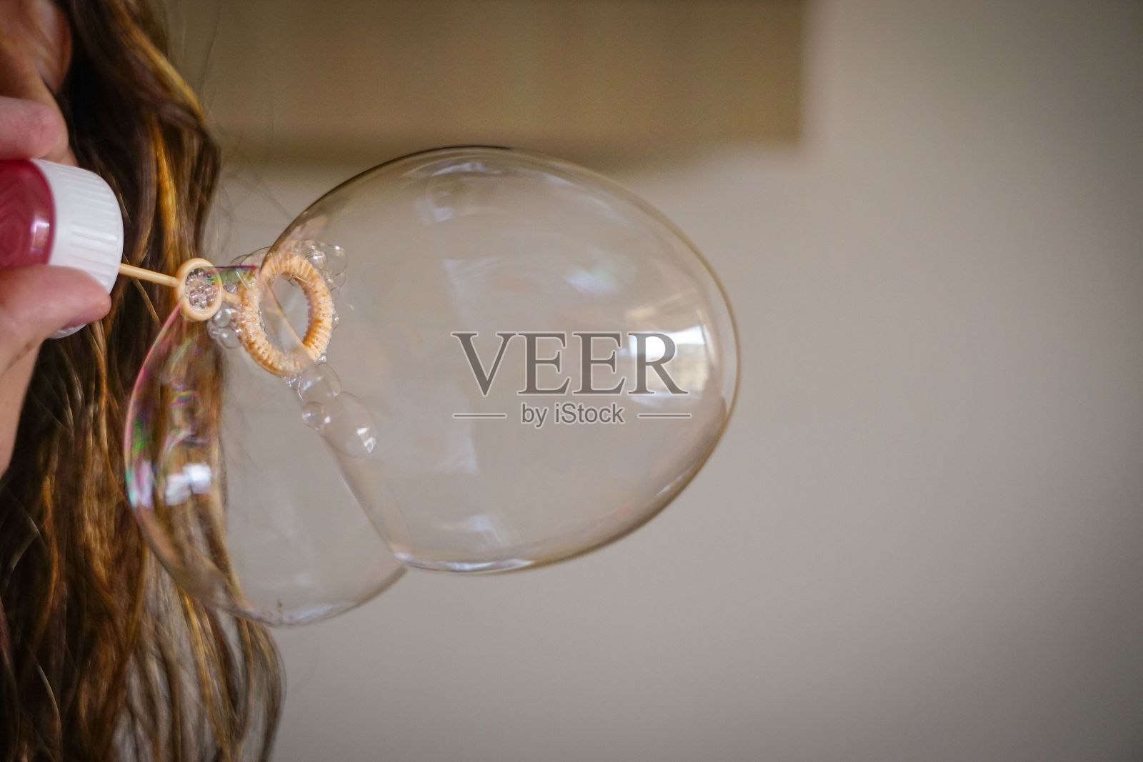 一个女人用肥皂水吹气制造气球的特写照片摄影图片