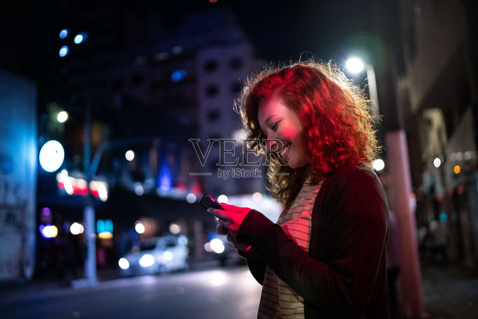 年轻女子晚上在街上使用手机照片摄影图片