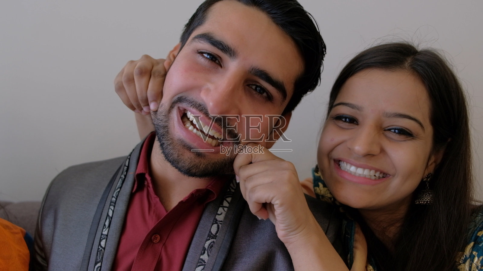 一对南亚夫妇对着镜头微笑，女孩捏了捏男人的脸颊照片摄影图片