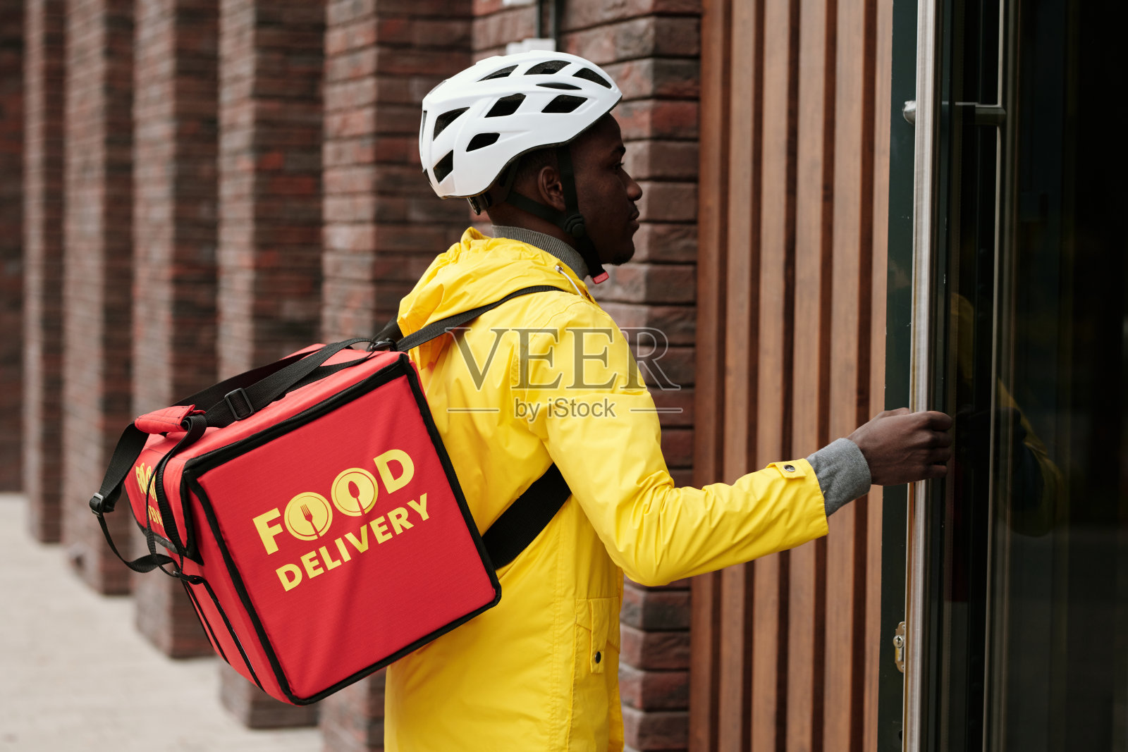 穿着夹克和头盔的年轻科里尔的侧视图打开门照片摄影图片