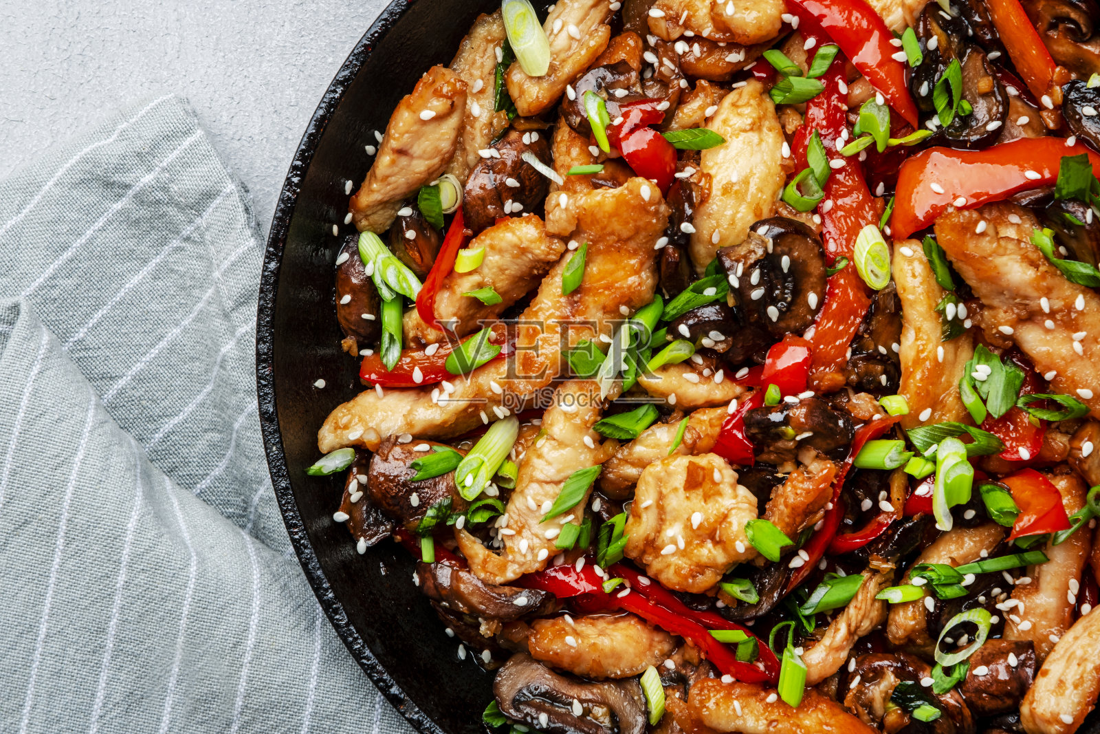 将鸡肉、红辣椒粉、香菇和香葱放入煎锅中翻炒。亚洲菜。灰色厨房桌面背景，俯视图，复制空间照片摄影图片