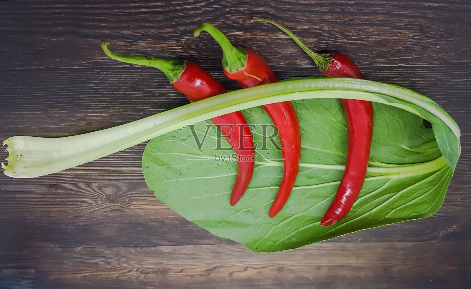 红辣椒，番茄和韭菜放在木桌上。五颜六色的蔬菜和食材。照片摄影图片