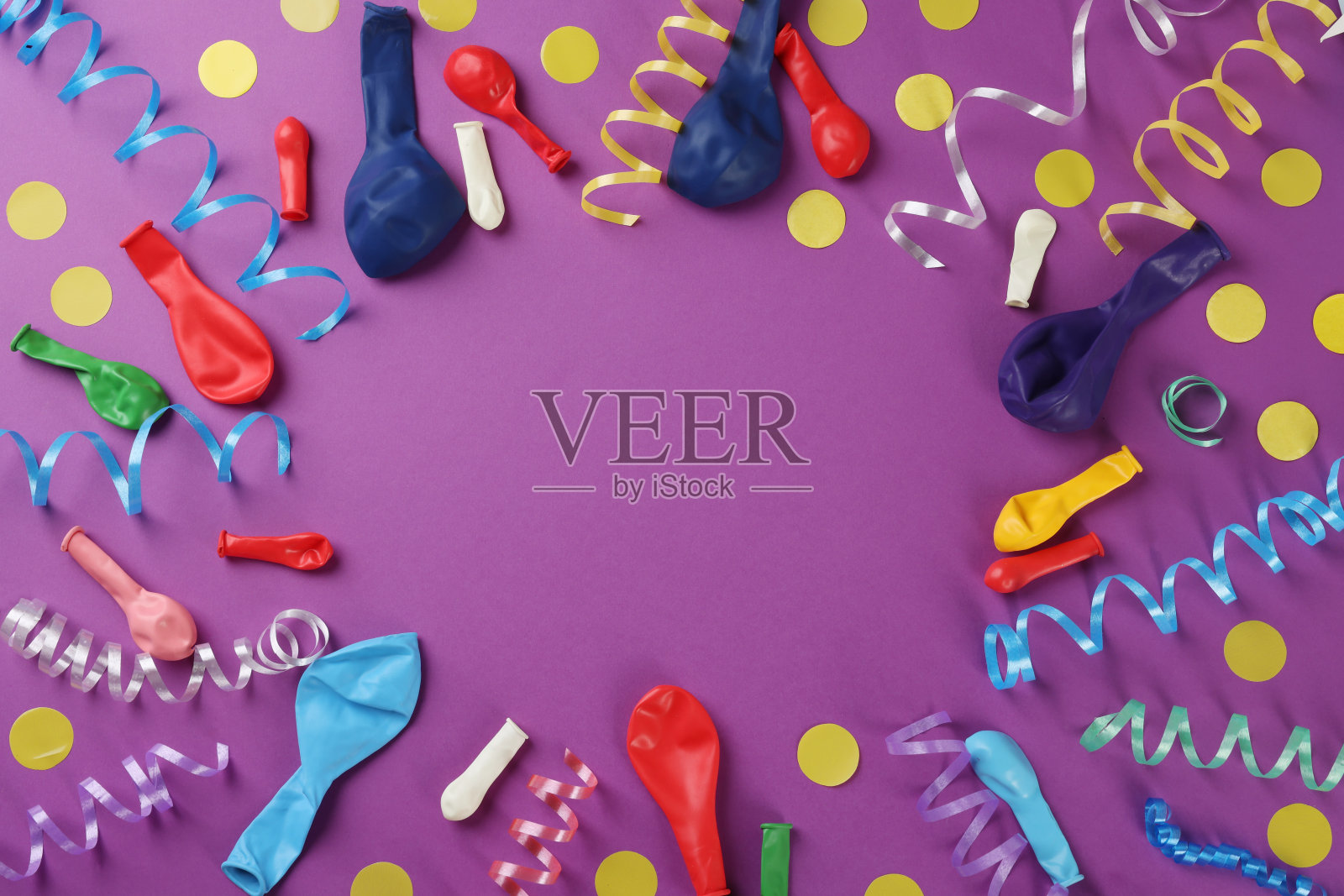 框架的彩色蛇形饰带和其他聚会配件在紫色的背景，平坦的铺设。文本空间照片摄影图片
