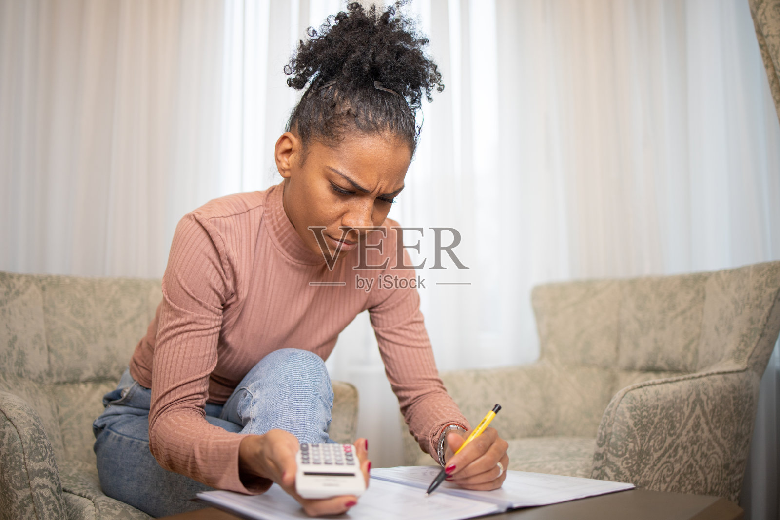 年轻女子用计算器计算账单和家庭财务照片摄影图片