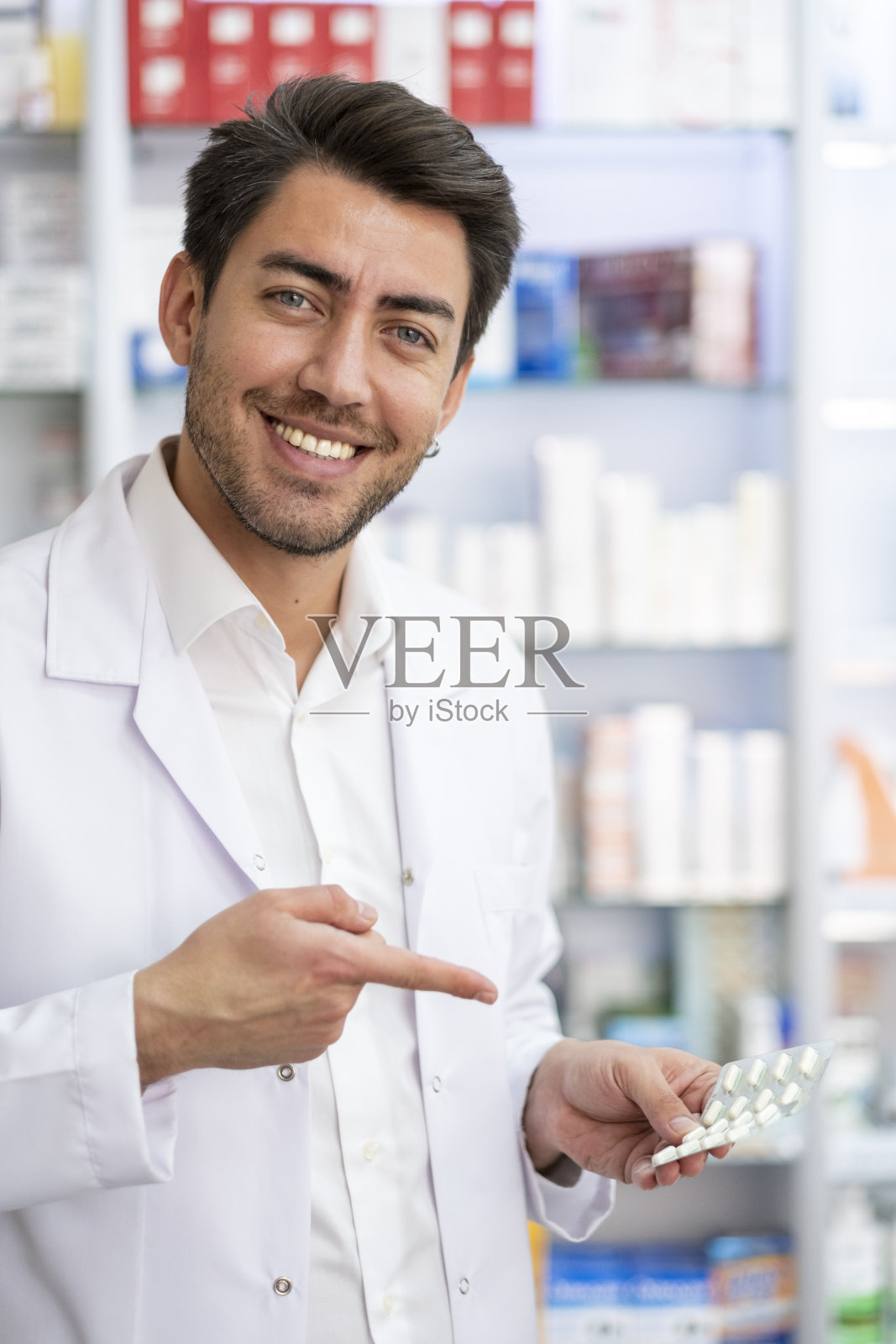 年轻的药剂师指着手里的药照片摄影图片