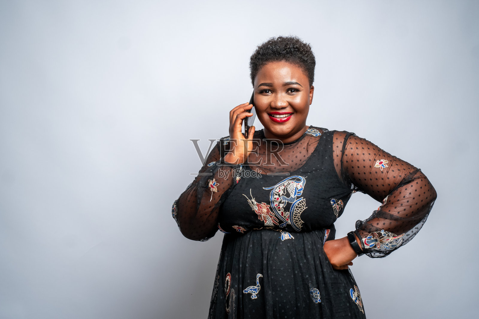 一个快乐的非裔美国女性对着白墙打电话照片摄影图片