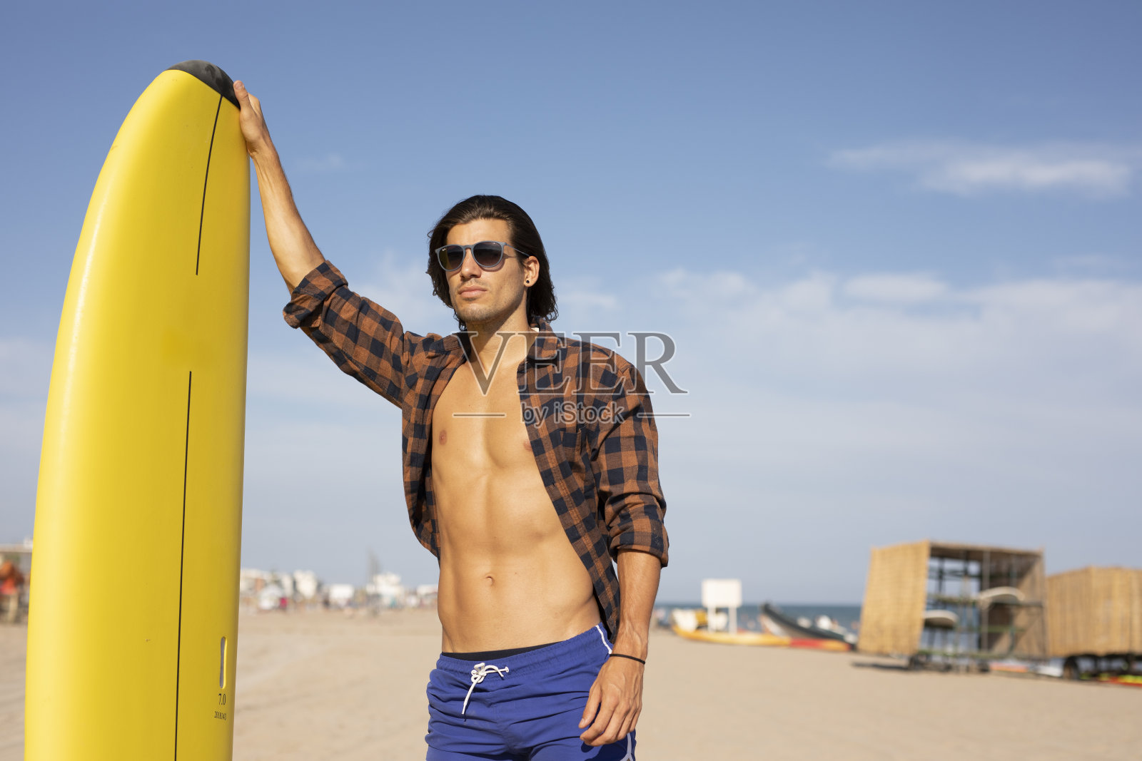 海滩上一个拿着冲浪板的年轻人。照片摄影图片