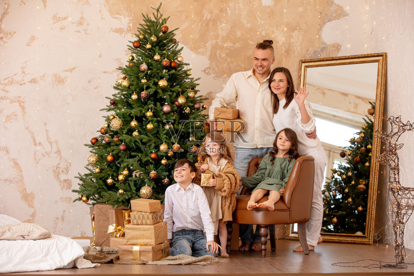 家庭——爸爸、妈妈和三个孩子，在家里一棵装饰好的圣诞树下快乐地庆祝圣诞节照片摄影图片