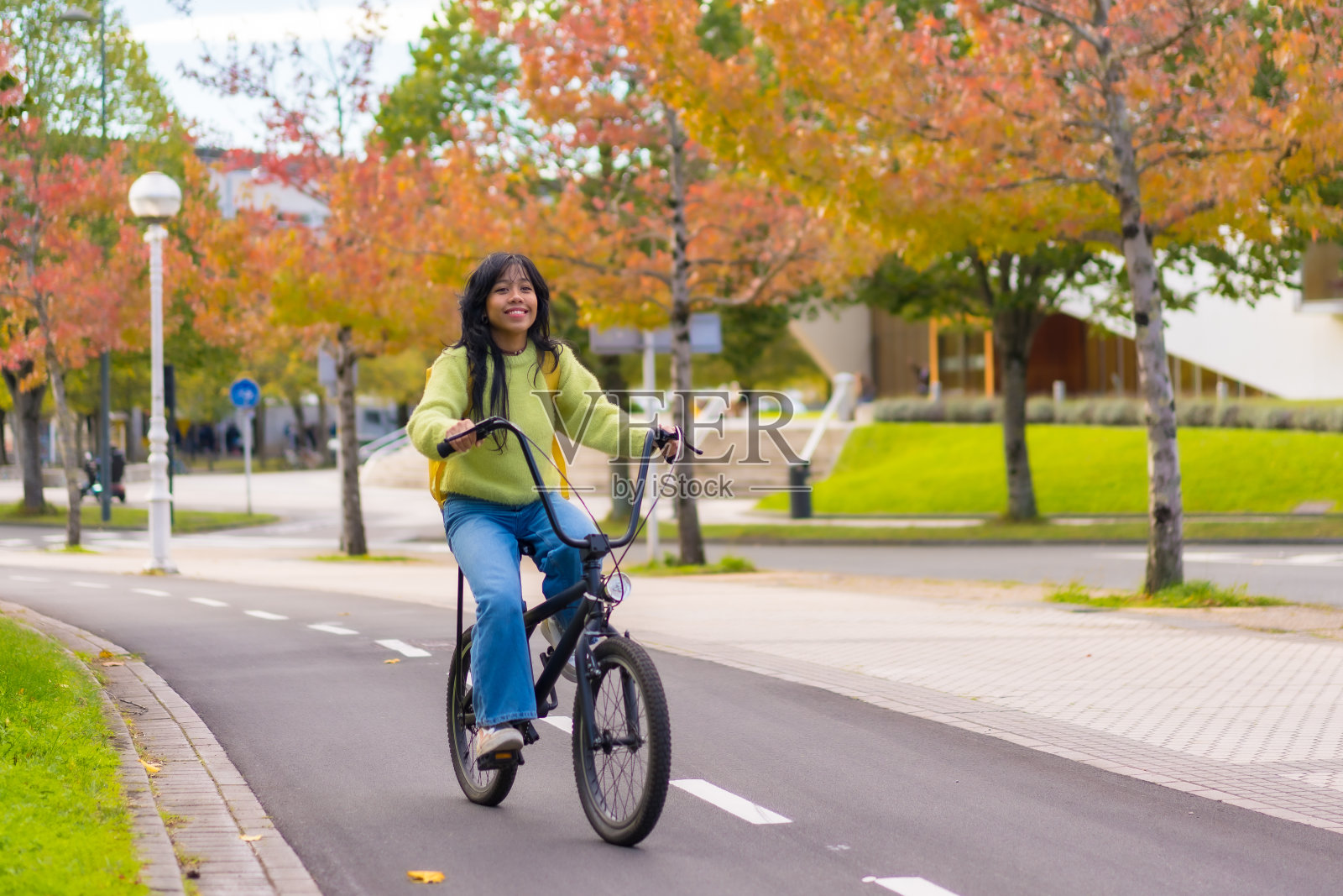 年轻的亚洲女学生微笑着骑着自行车在秋天上学的路上，健康的生活，环保照片摄影图片