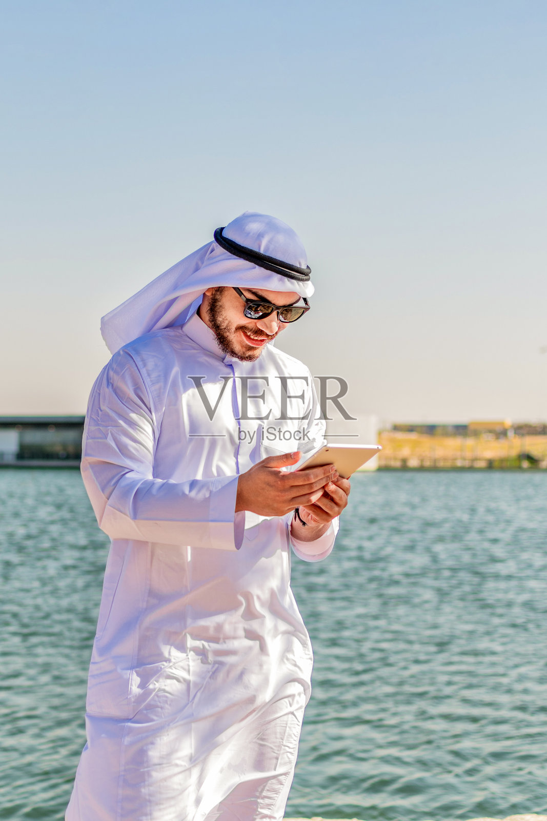 垂直拍摄的穆斯林男性，穿着传统服装，在平板电脑上查看内容照片摄影图片