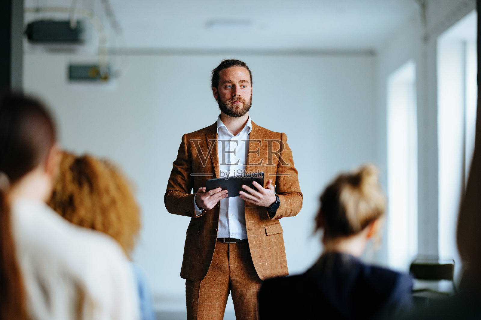 一名严肃的商人手持平板电脑在演讲中与观众交谈照片摄影图片