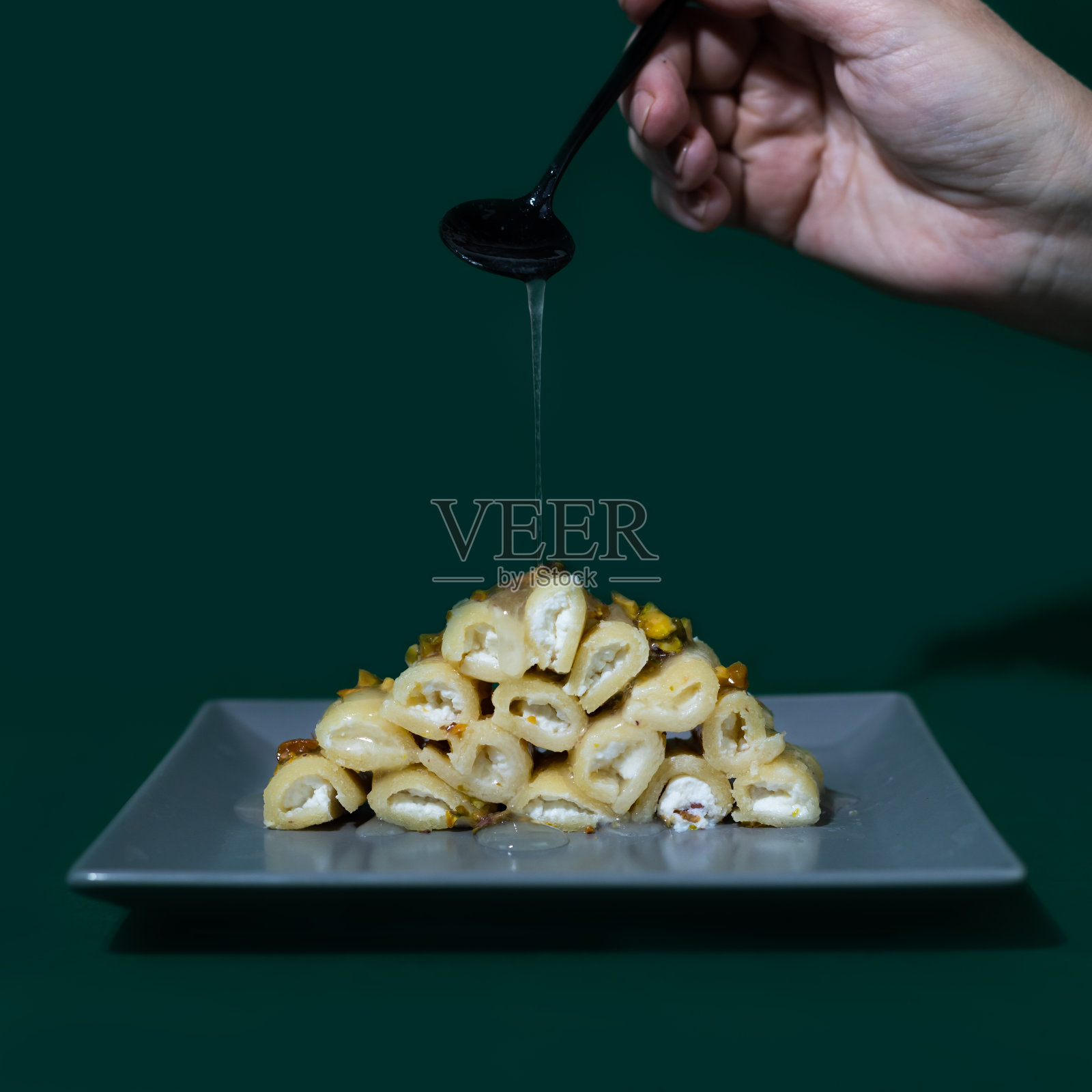 哈拉韦El Jibn卷阿拉伯甜适应生酮饮食。用马苏里拉芝士、杏仁粉、赤糖醇糖浆、玫瑰水调制而成的甜点，配以奶油芝士和开心果照片摄影图片