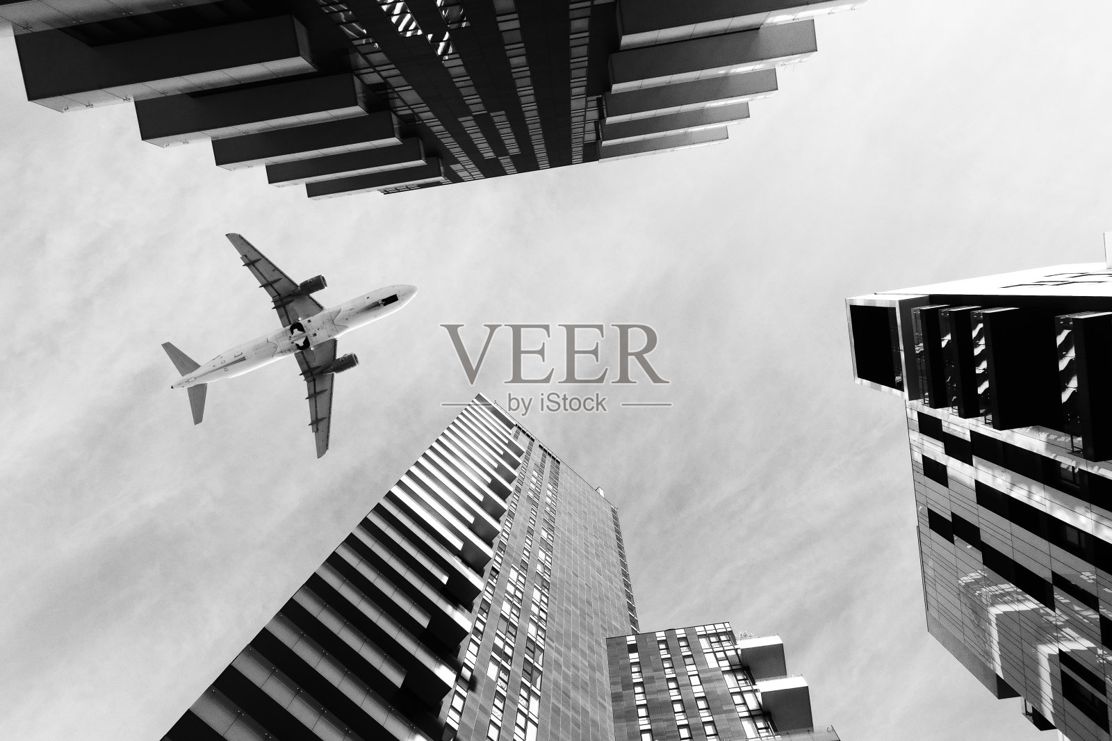 飞机飞过摩天大楼。照片摄影图片